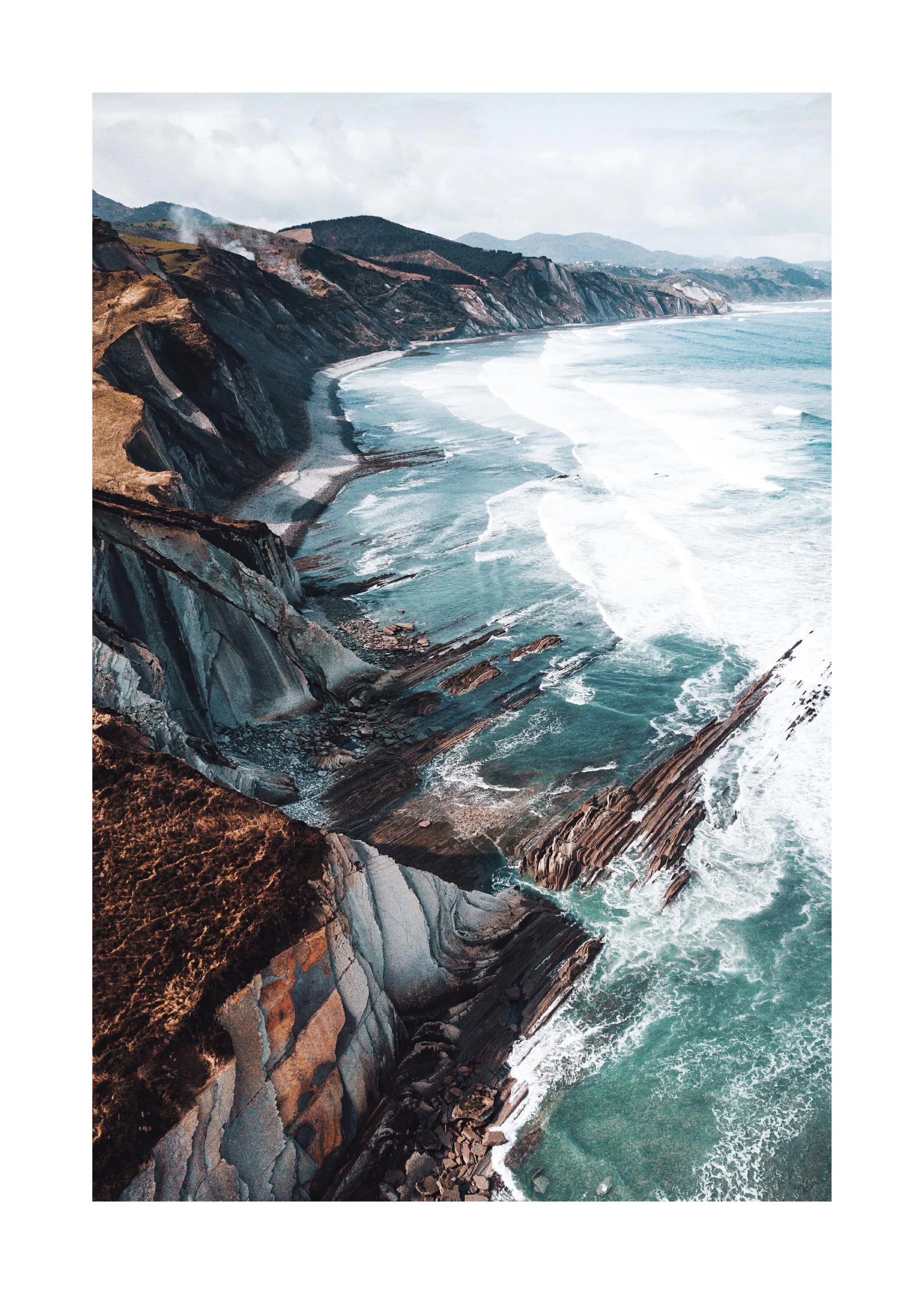 Ein Poster einer rauen Küstenlandschaft mit Klippen, die ins Meer ragen, und Wellen, die auf Felsformationen treffen.