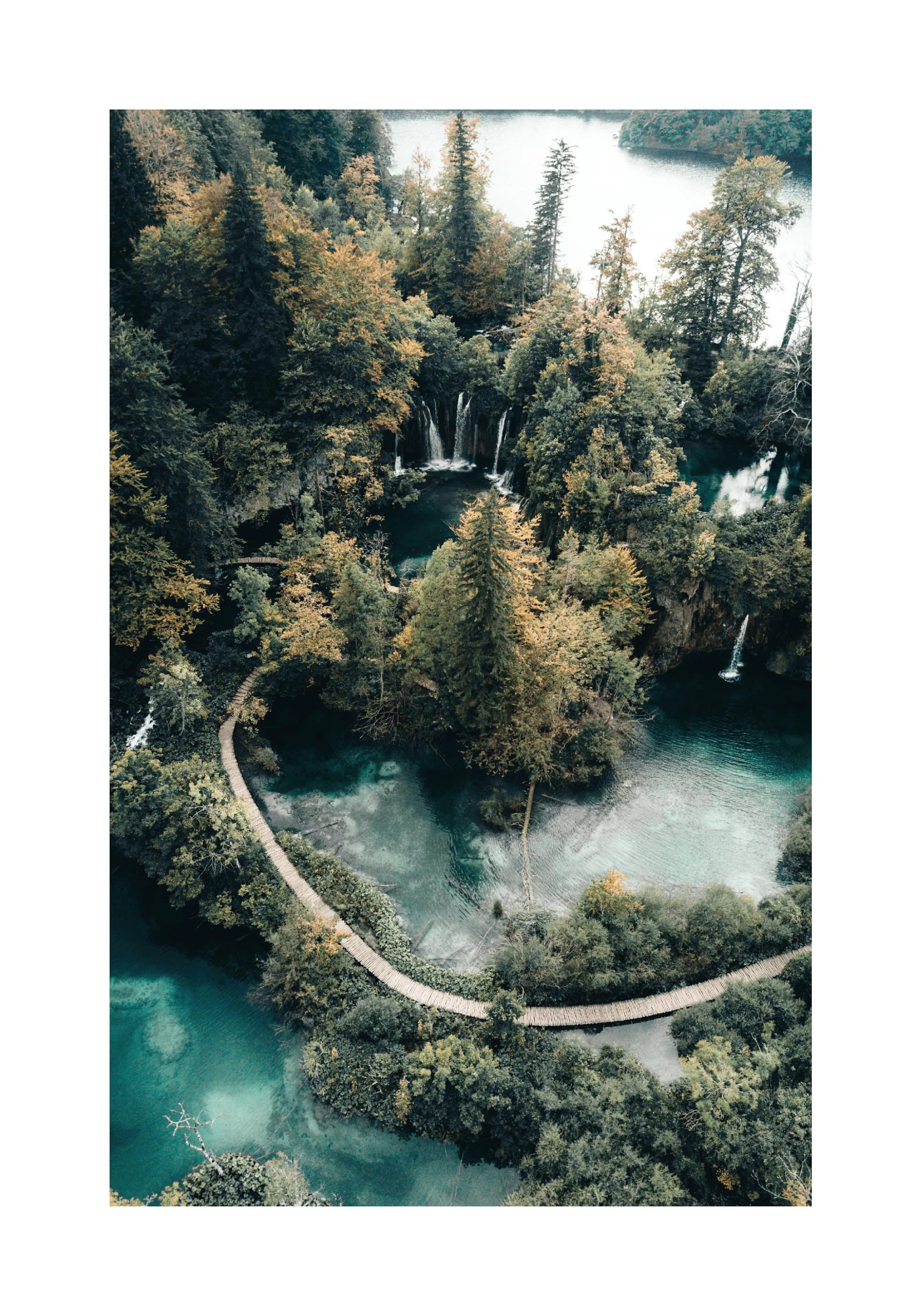 A poster featuring an aerial view of turquoise lakes, lush green and golden trees, waterfalls, and a winding wooden walkway.