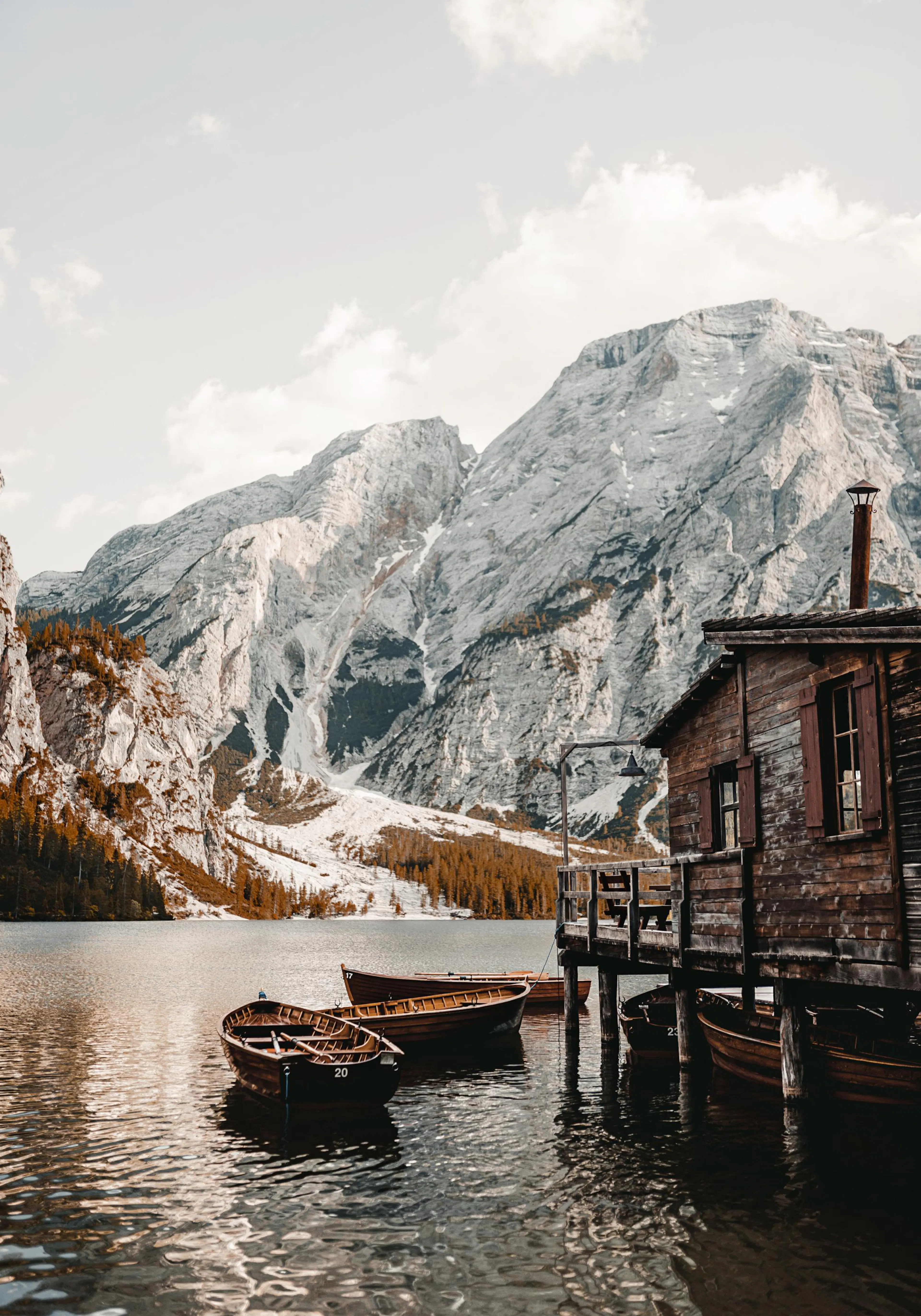 A poster featuring a moody lake scene with wooden boats, a boathouse, and mountains in the background.