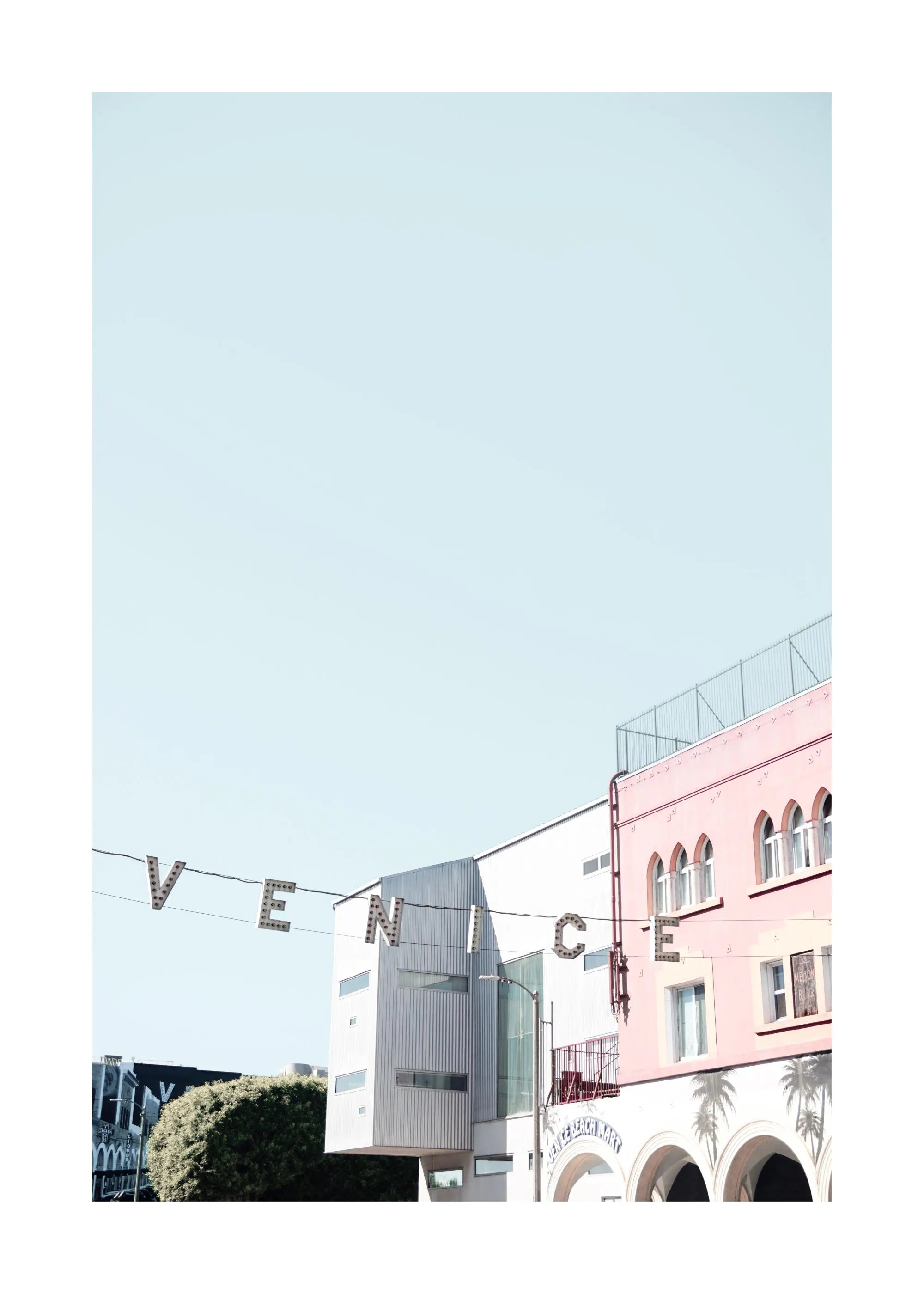 En poster som visar en rosa byggnad med valv och palmreflektioner, och skylten VENICE under en ljusblå himmel.