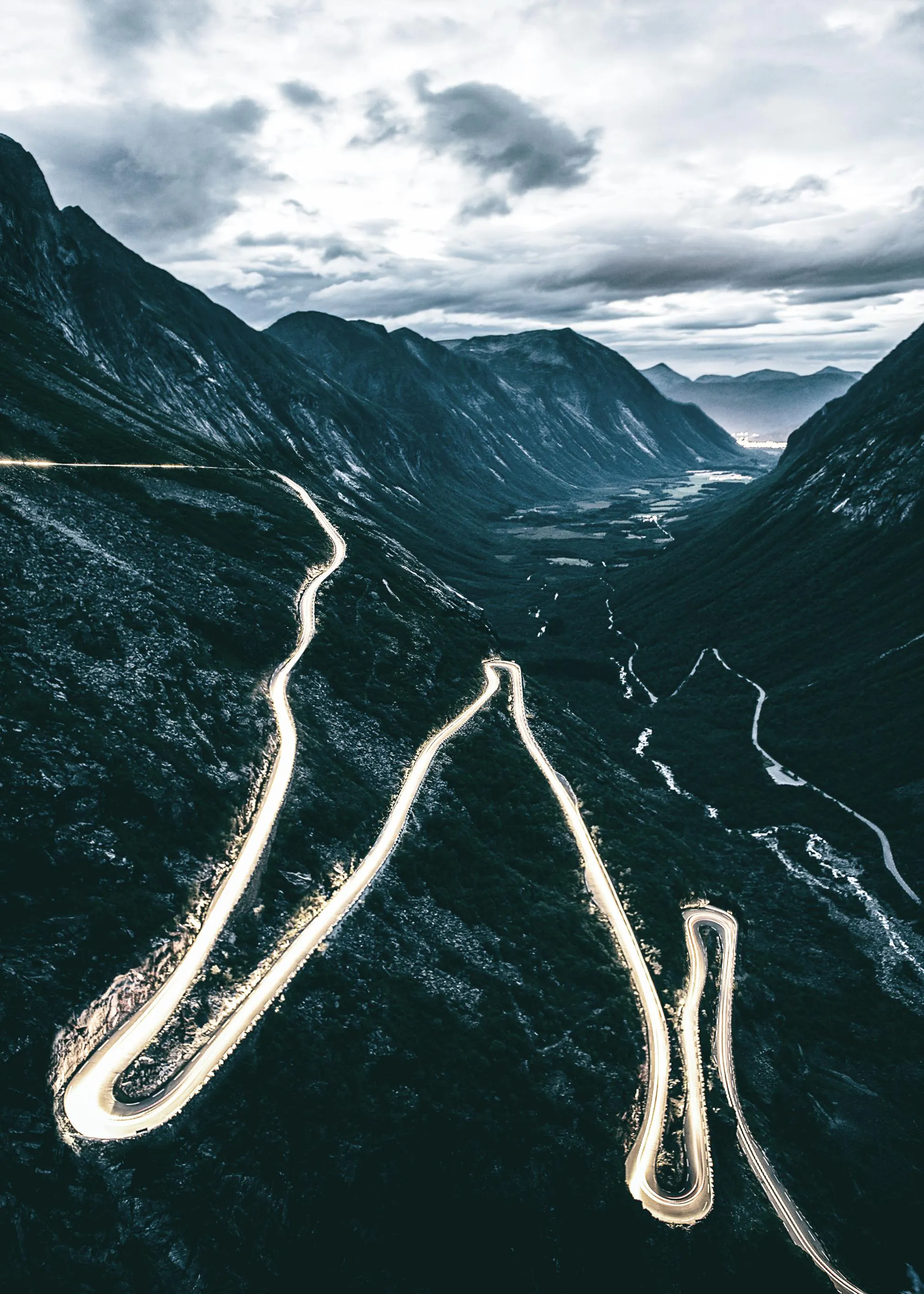Poster einer Berglandschaft bei Nacht mit leuchtenden Serpentinenstraßen und einem Tal mit Fluss.