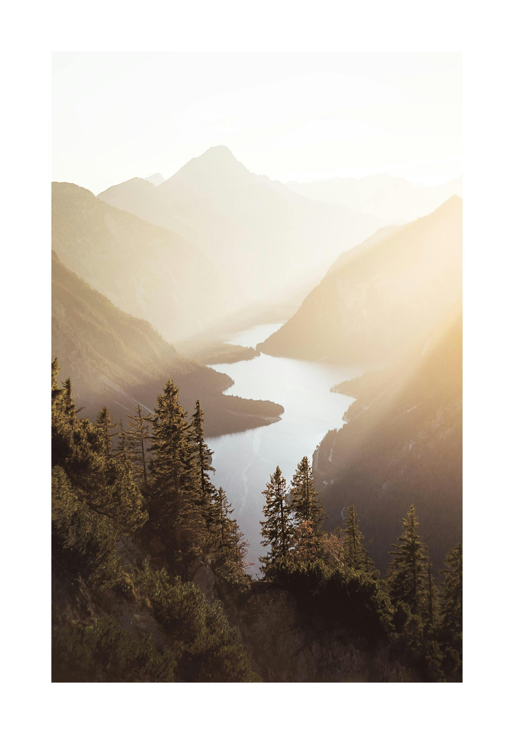 A poster depicting a serene lake nestled between majestic mountains, with sunlight casting a golden glow over the scene.