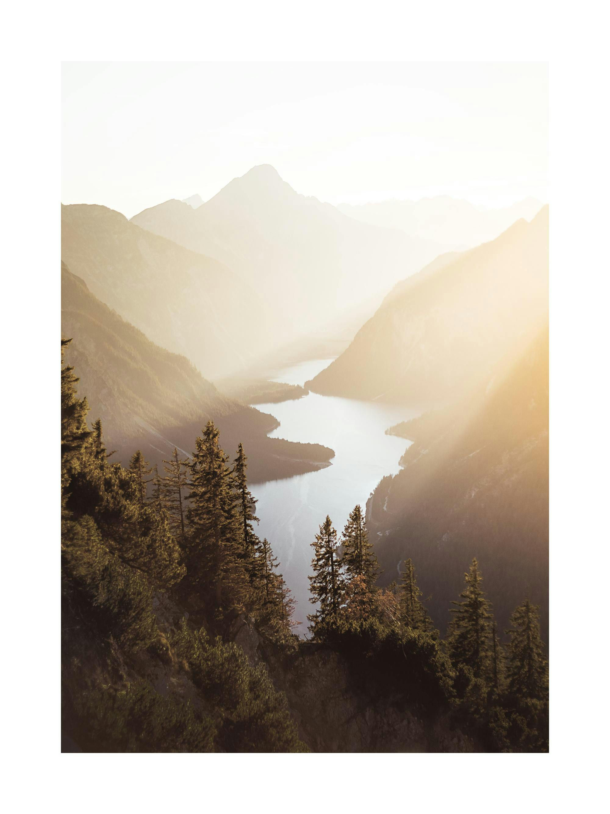 A poster depicting a serene mountain landscape with a calm lake winding through a valley, bathed in warm golden sunlight.