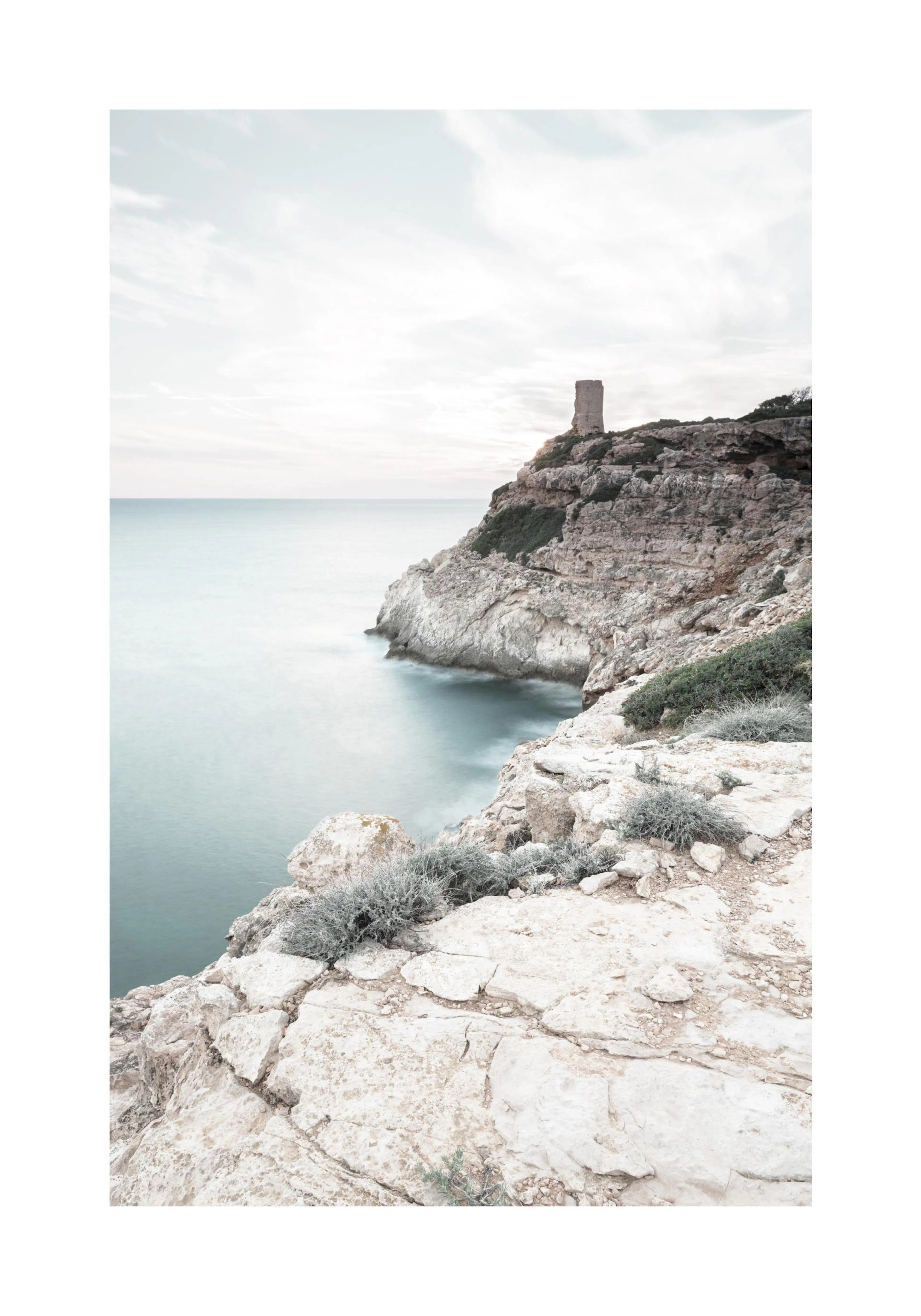 A poster featuring a rugged cliffside with an old stone tower overlooking a calm, pale blue sea under a soft, cloudy sky.