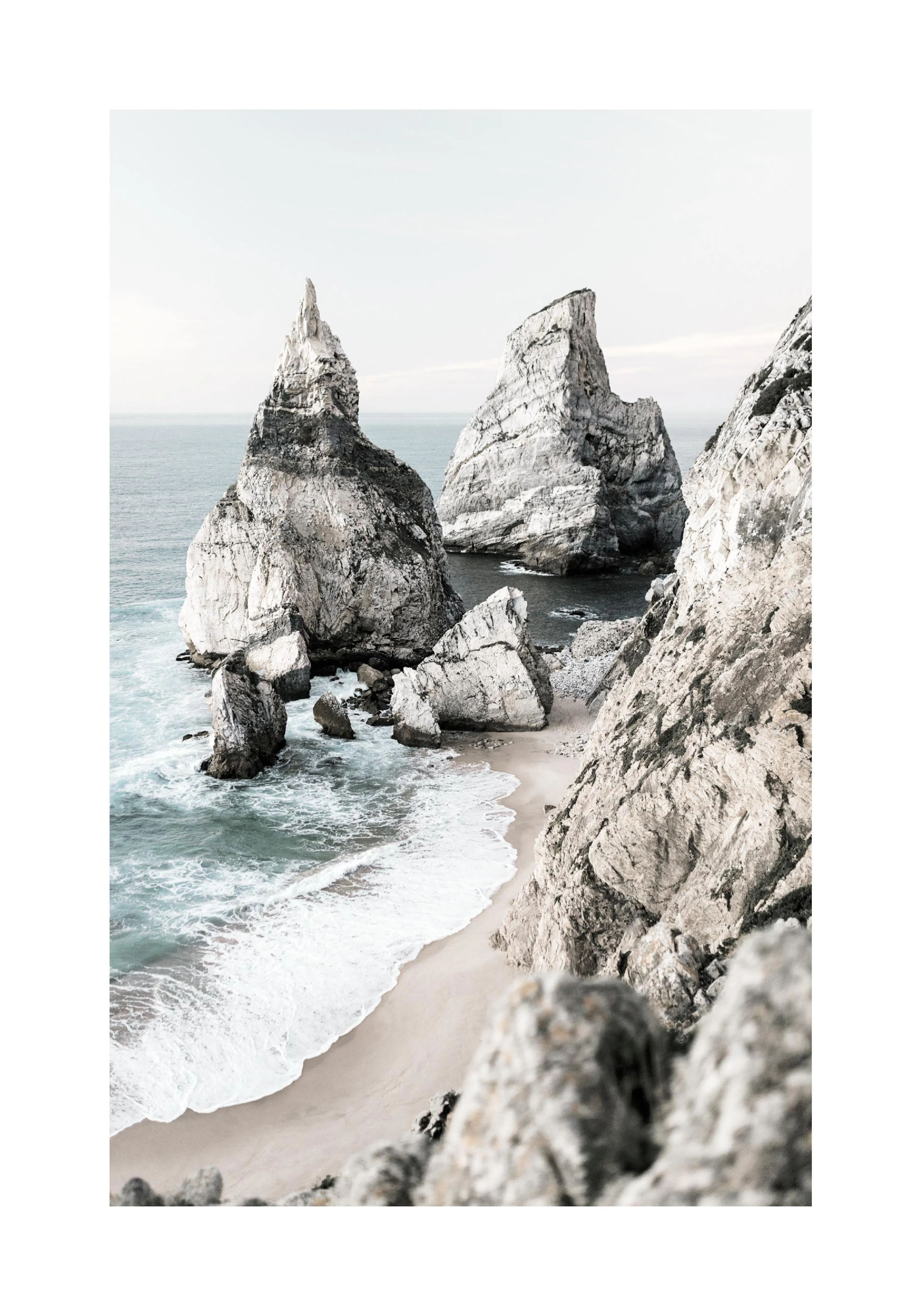 A poster featuring a dramatic coastline with large, craggy rock formations extending into the ocean, with waves breaking on a sa