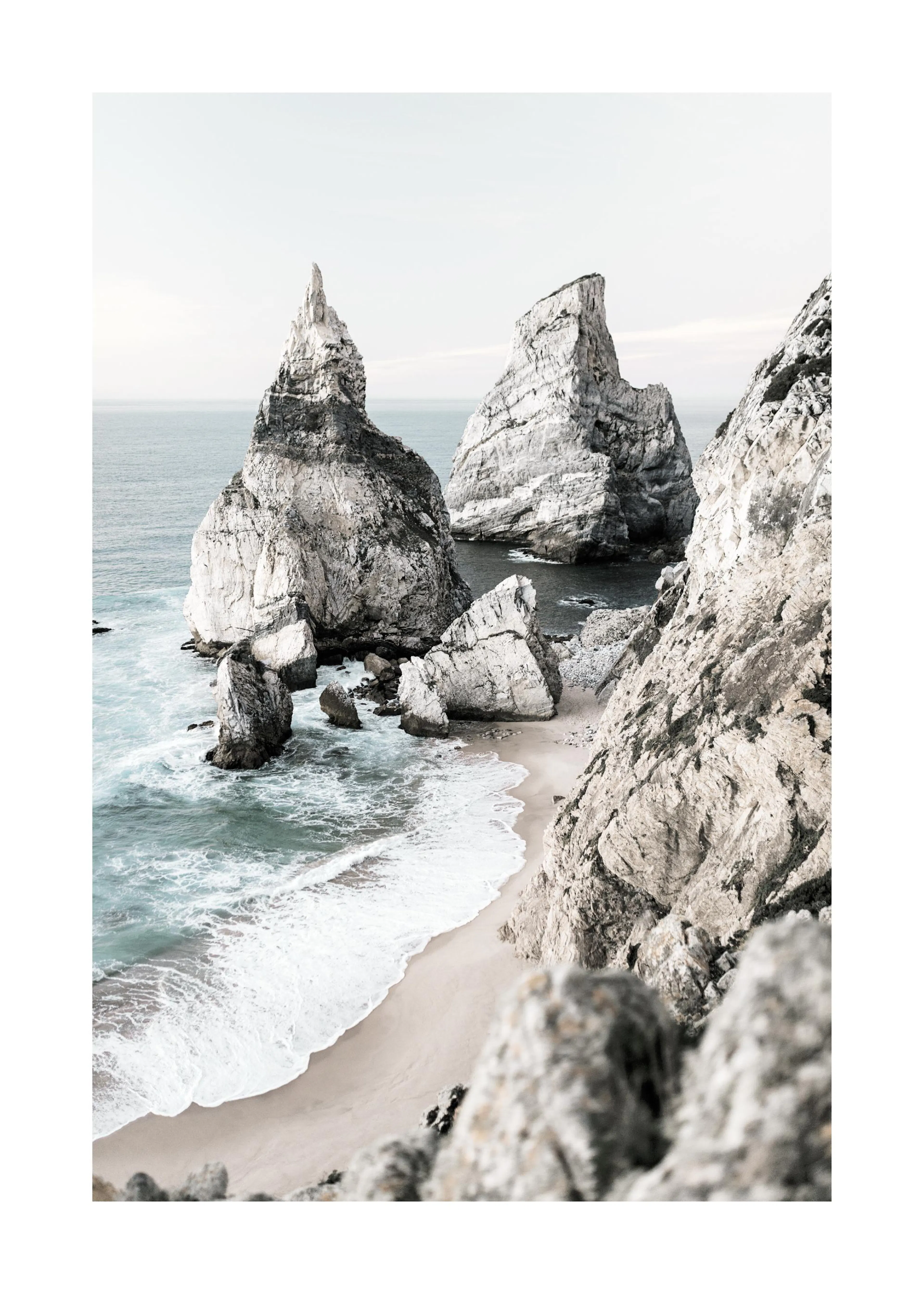 Poster einer felsigen Küstenlandschaft mit zwei markanten Felsnadeln im Meer und einer kleinen Bucht mit Sandstrand.