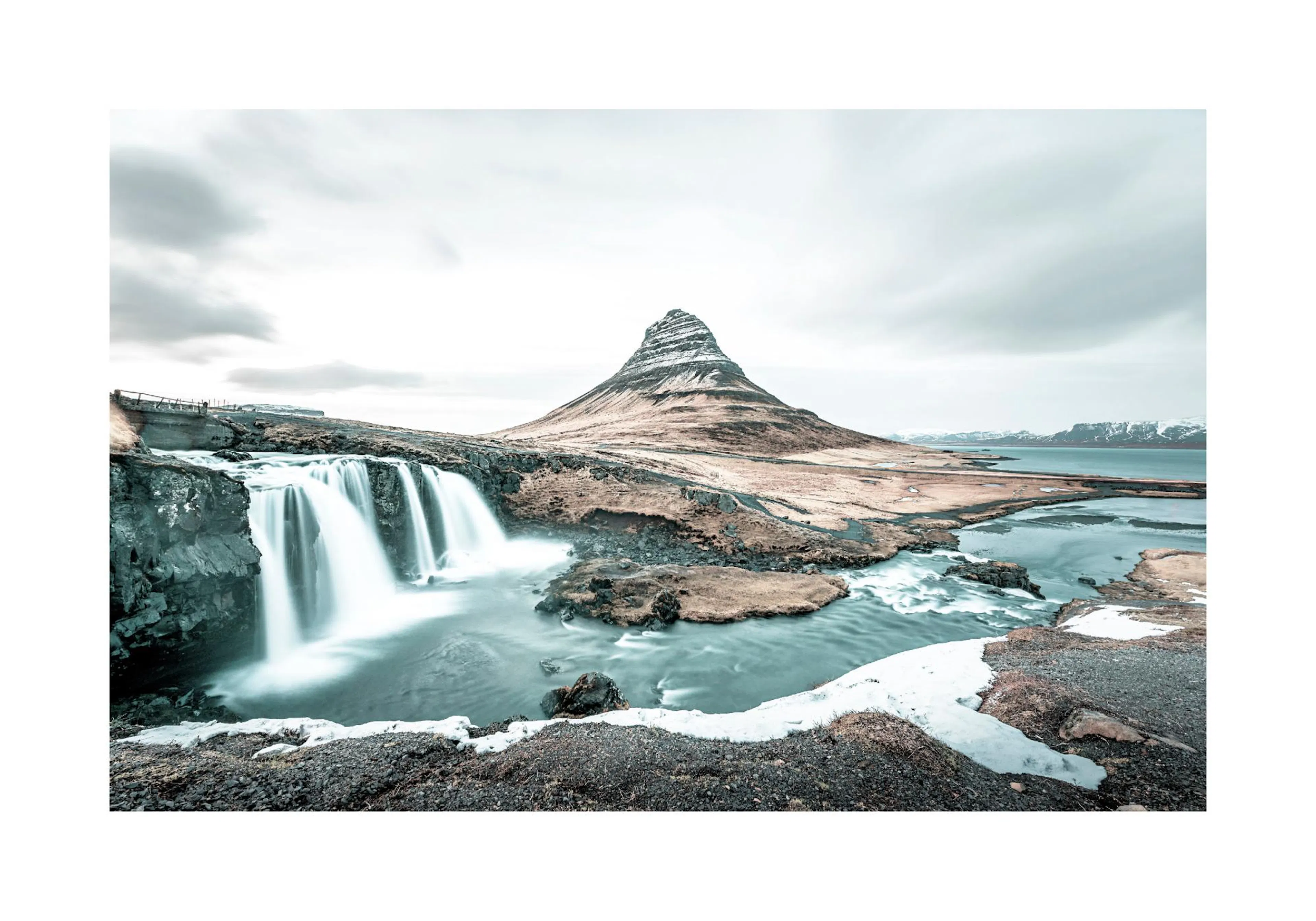 Poster: Panoramablick auf den Wasserfall Kirkjufellsfoss und den Berg Kirkjufell in Island unter bewölktem Himmel.