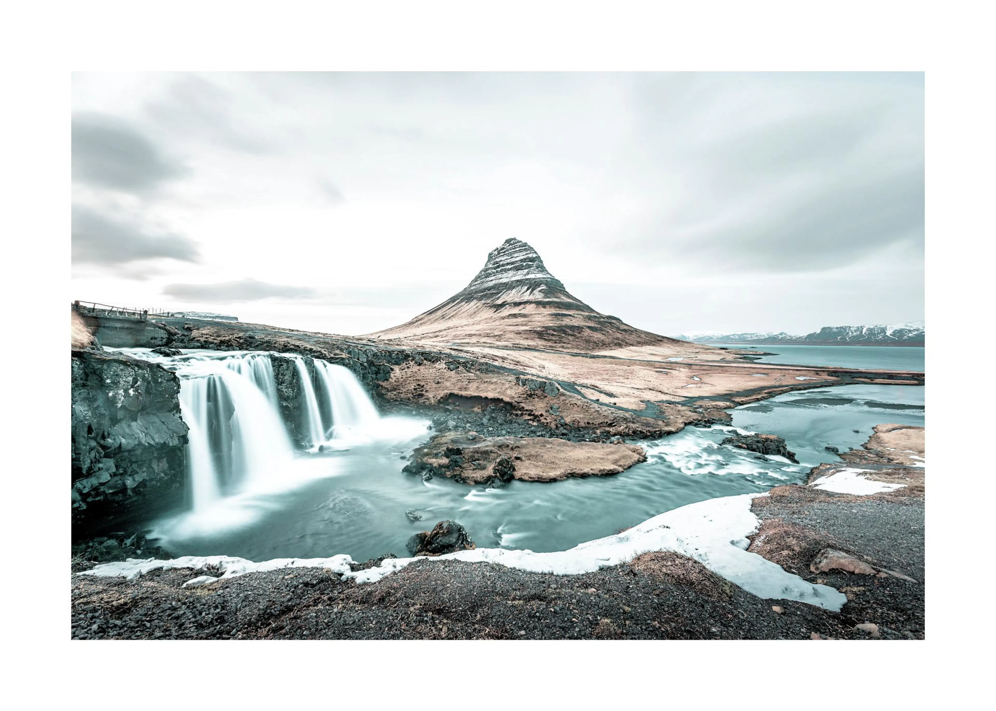 Poster: Panoramablick auf den Wasserfall Kirkjufellsfoss und den Berg Kirkjufell in Island unter bewölktem Himmel.