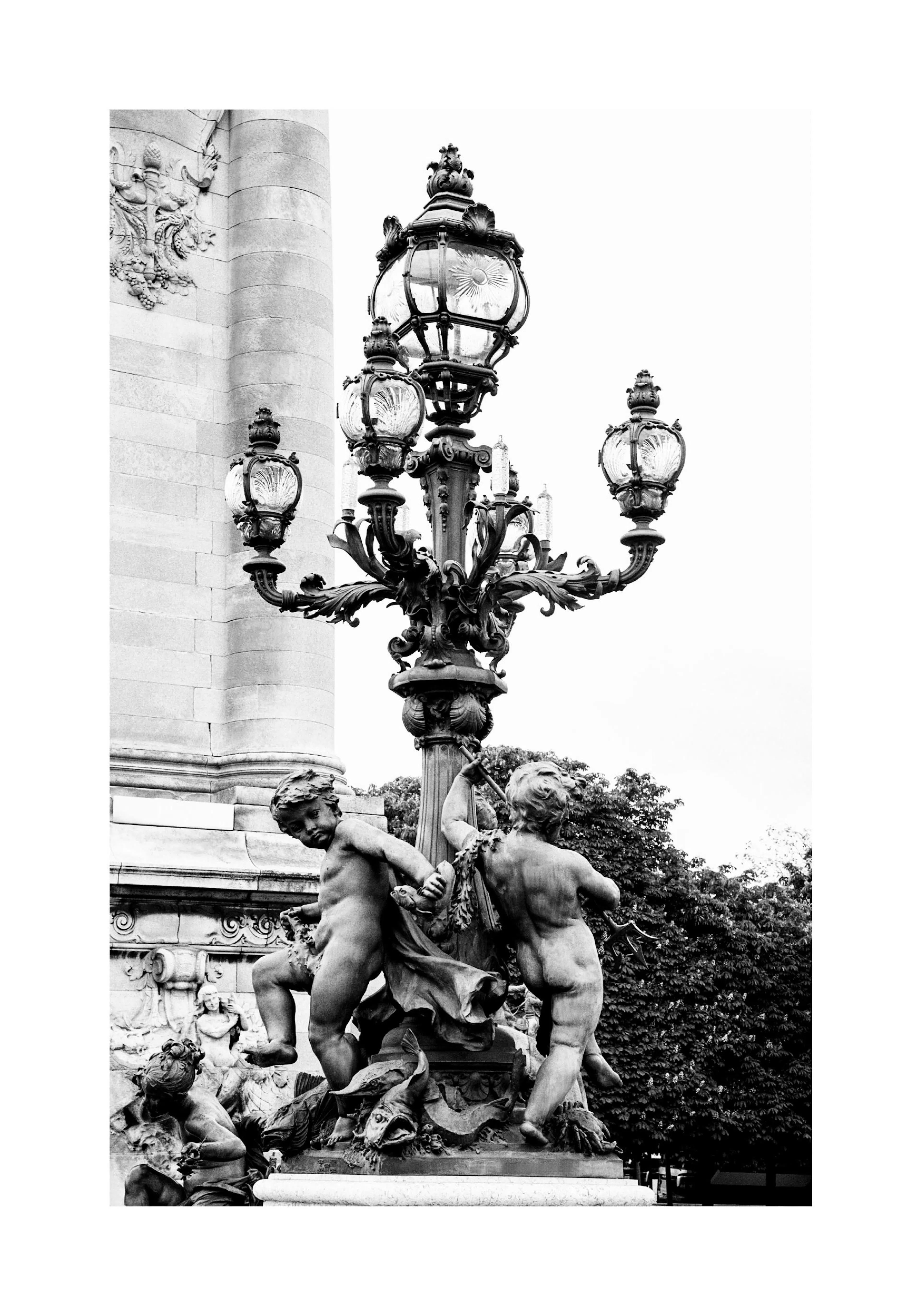 A poster of a black and white image of a detailed ornate lamp post featuring cherub statues at its base.