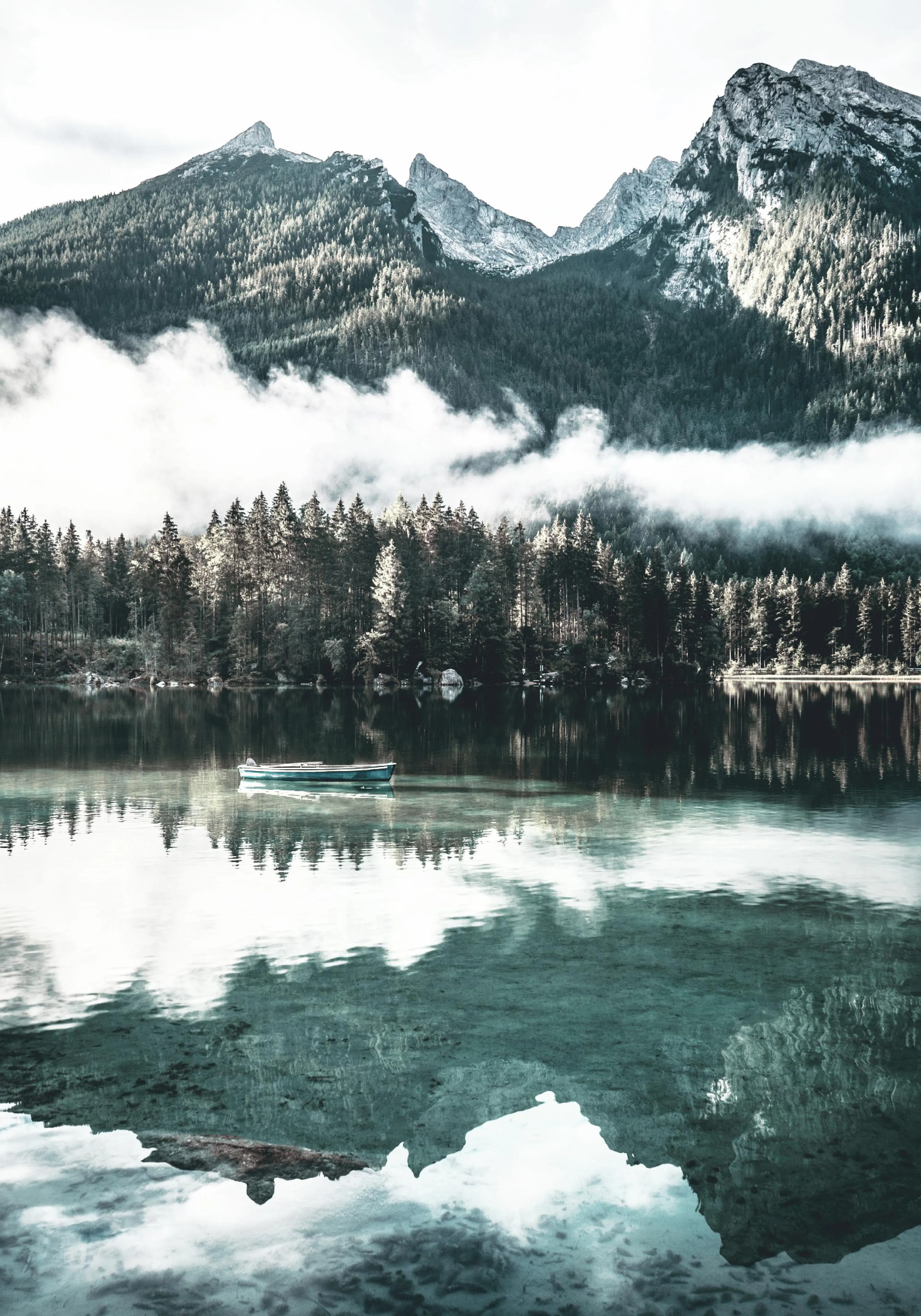 A poster featuring a peaceful lake with a small boat, surrounded by pine forests and misty mountains under a bright sky.