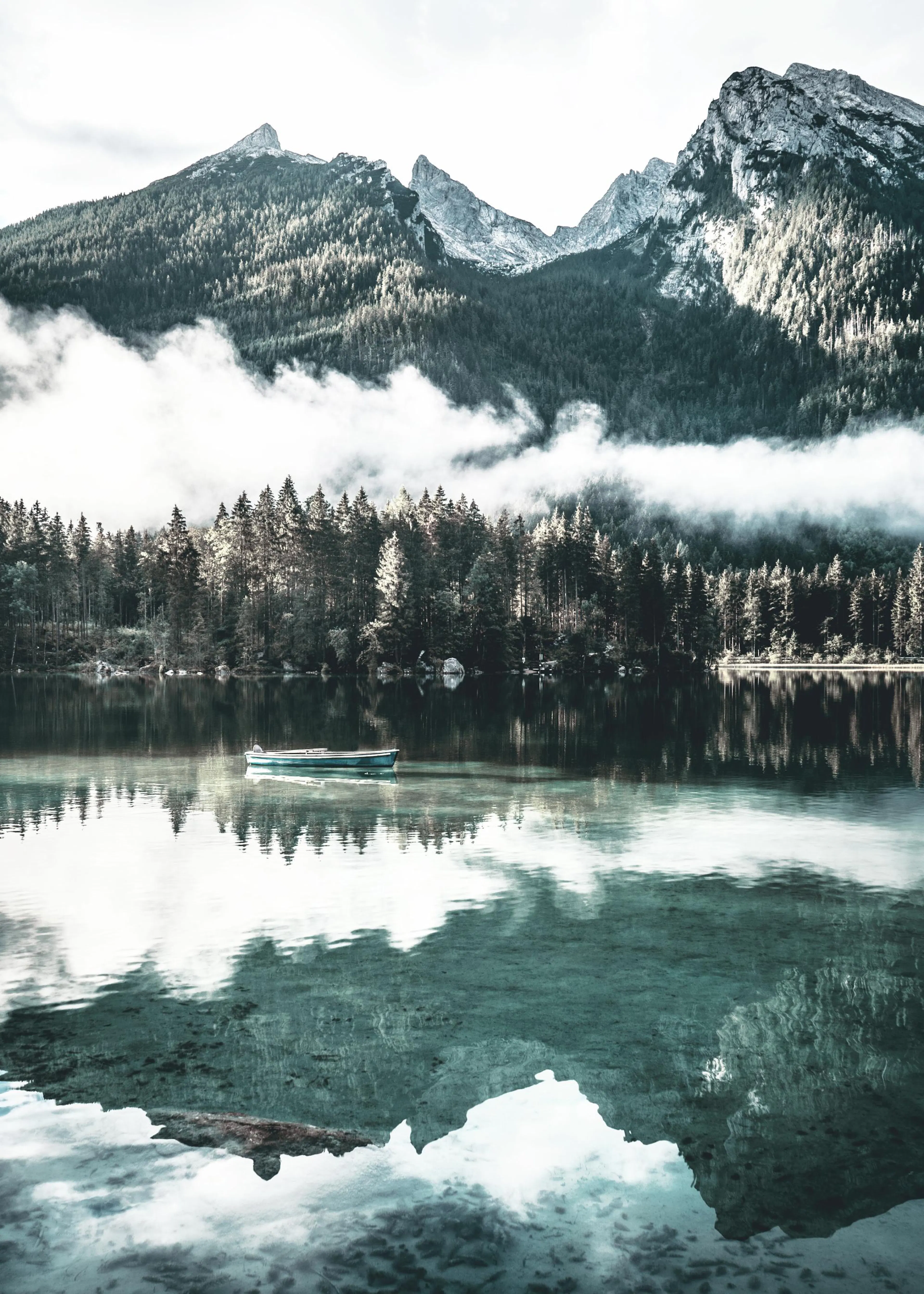 Poster: Ein Ruderboot auf einem klaren Bergsee umgeben von einem Nadelwald, mit den Gipfeln der Alpen im Hintergrund.