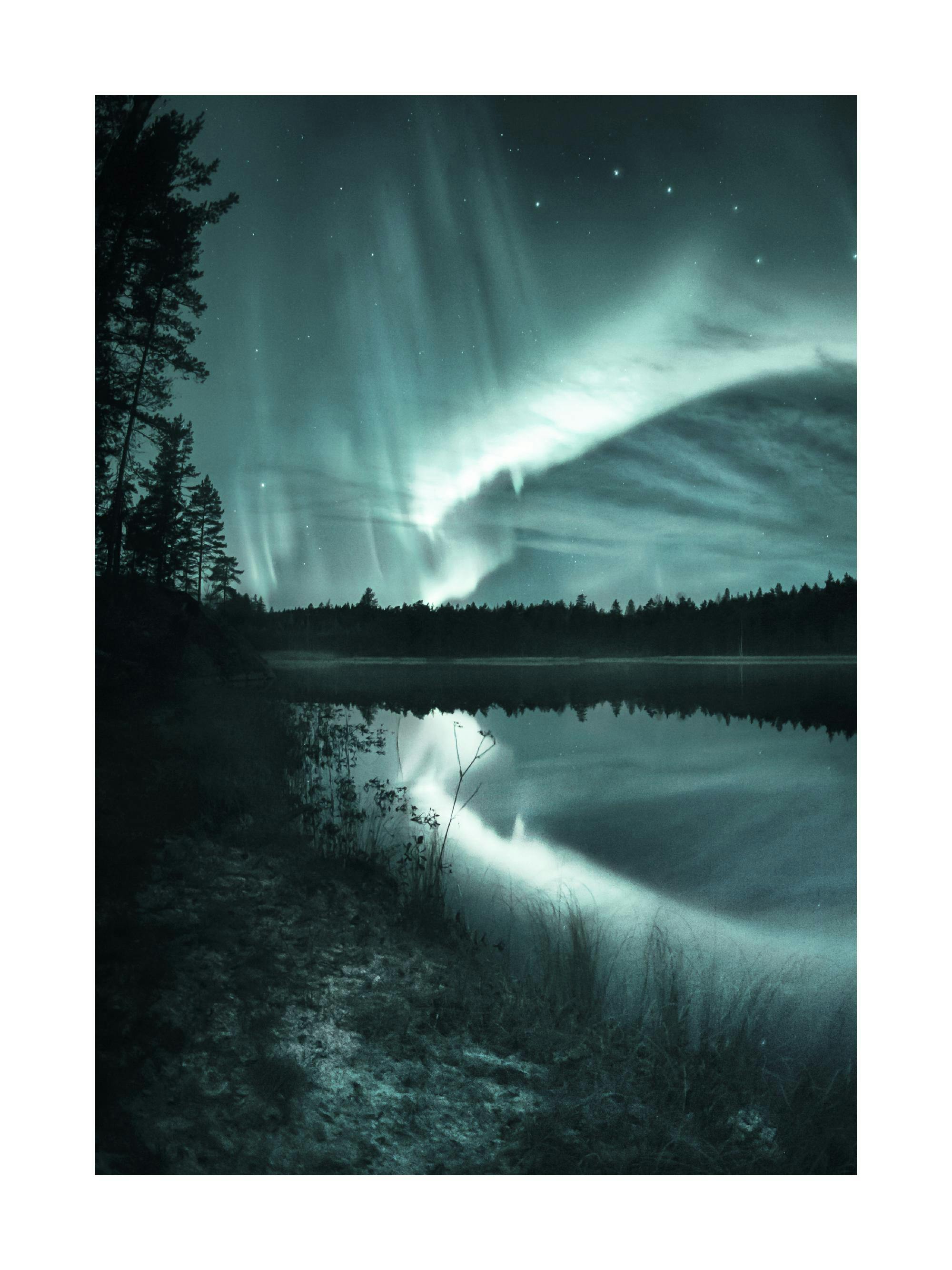 Plakat przedstawiający jezioro otoczone lasem, z zielono-niebieską zorzą polarną odbijającą się w wodzie.