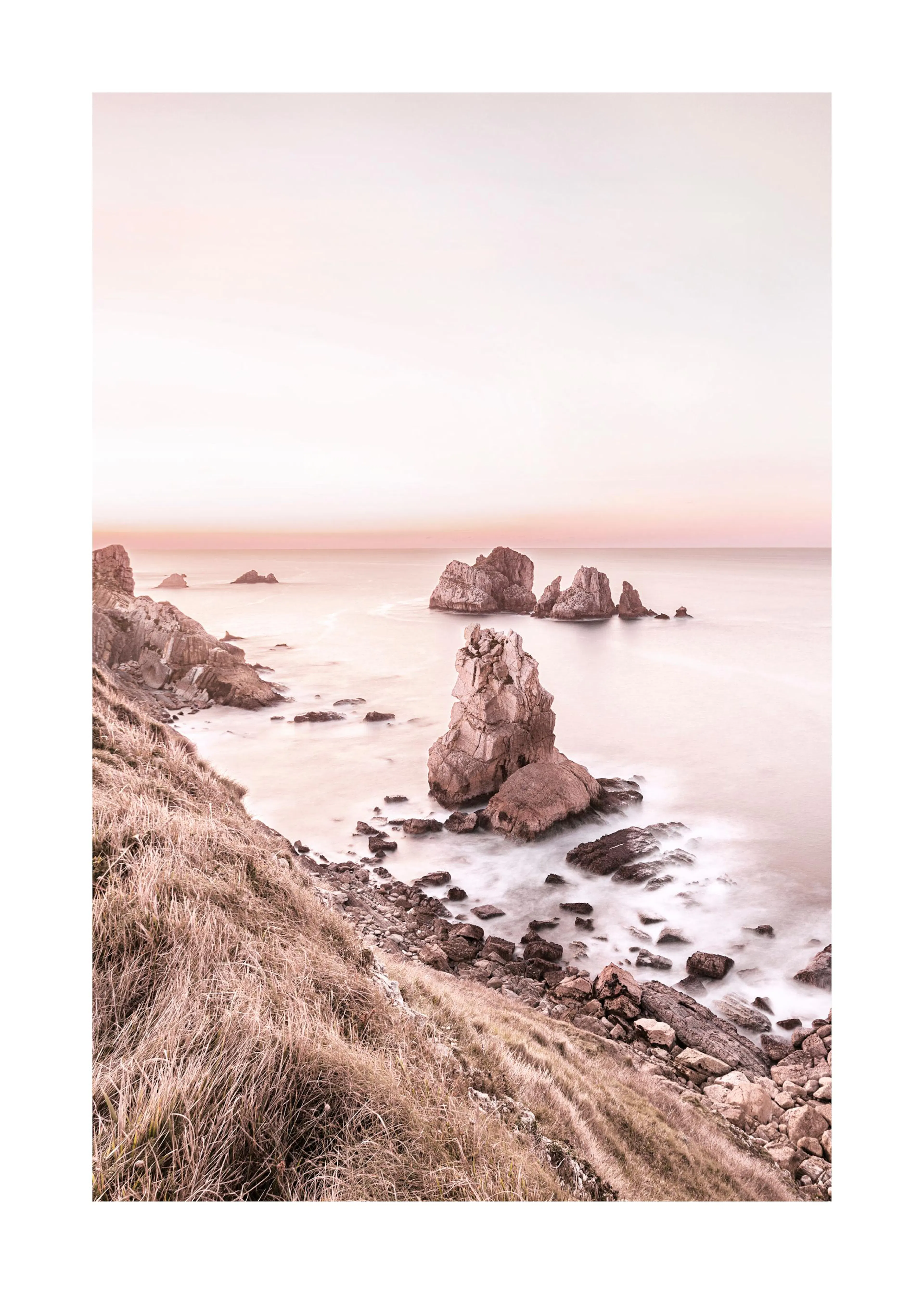 Poster: Küstenlandschaft bei Sonnenuntergang mit zerklüfteten Felsen im Meer und weichem, nebligem Wasser.