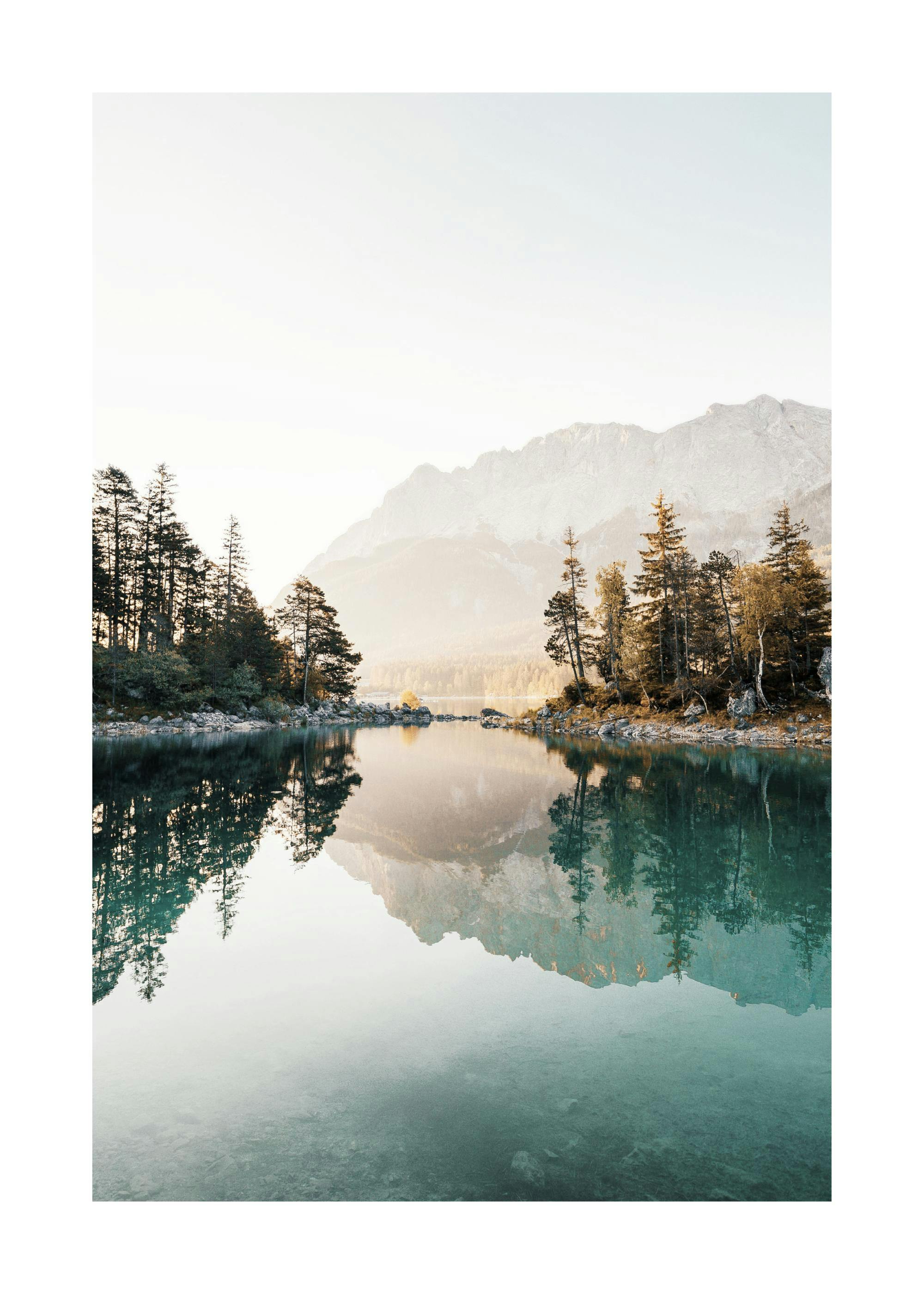 A poster featuring a calm lake reflecting tall evergreen trees and a majestic mountain range under a light sky.