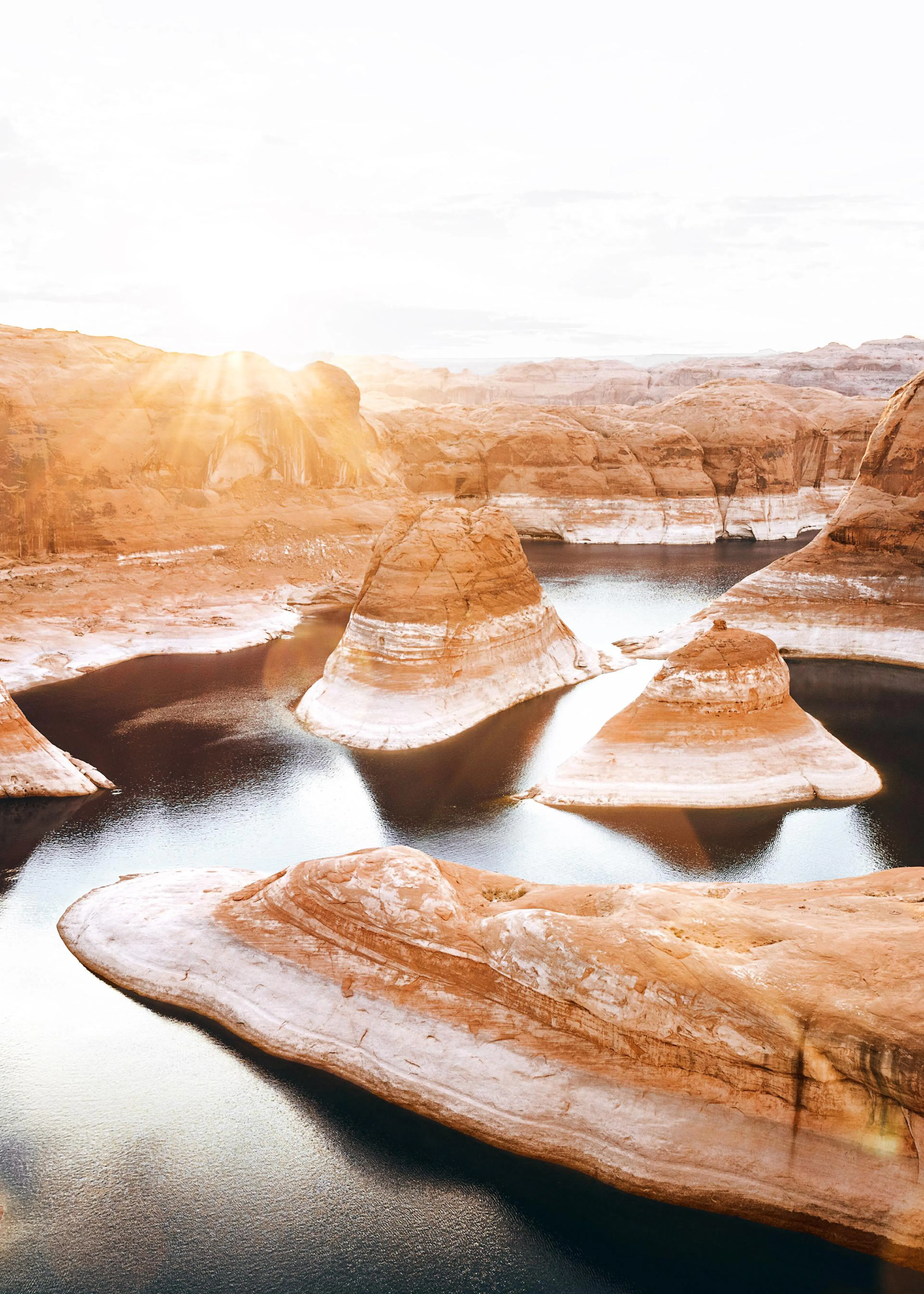 Poster: Eine Landschaftsaufnahme des Lake Powell bei Sonnenuntergang, mit orangefarbenen Felsformationen und ruhigem Wasser.