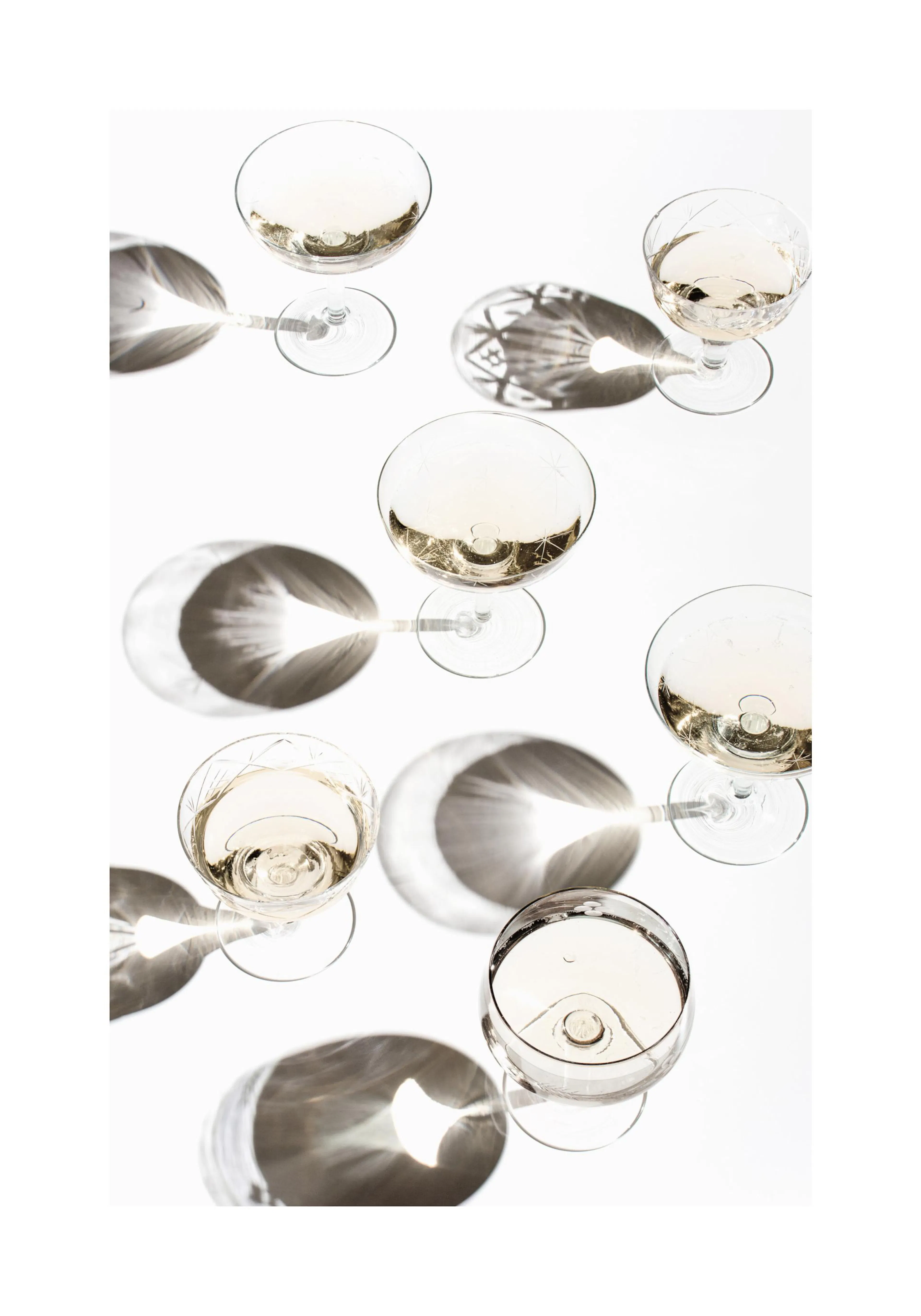 A poster featuring an overhead view of six champagne glasses with light reflections and shadows on a white background.