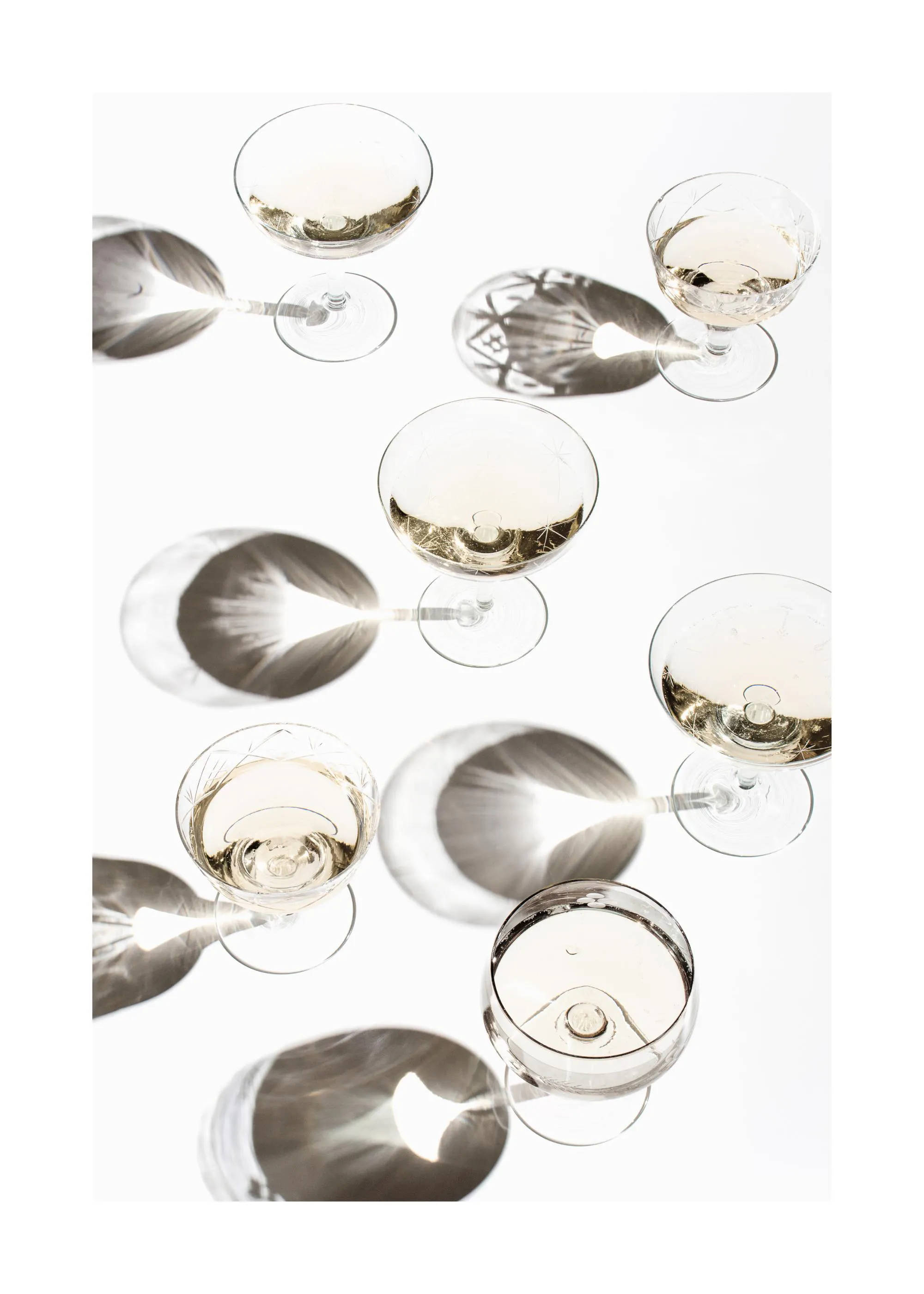 Poster de verres à cocktail remplis dune boisson gazeuse claire avec des ombres grises sur un fond blanc.