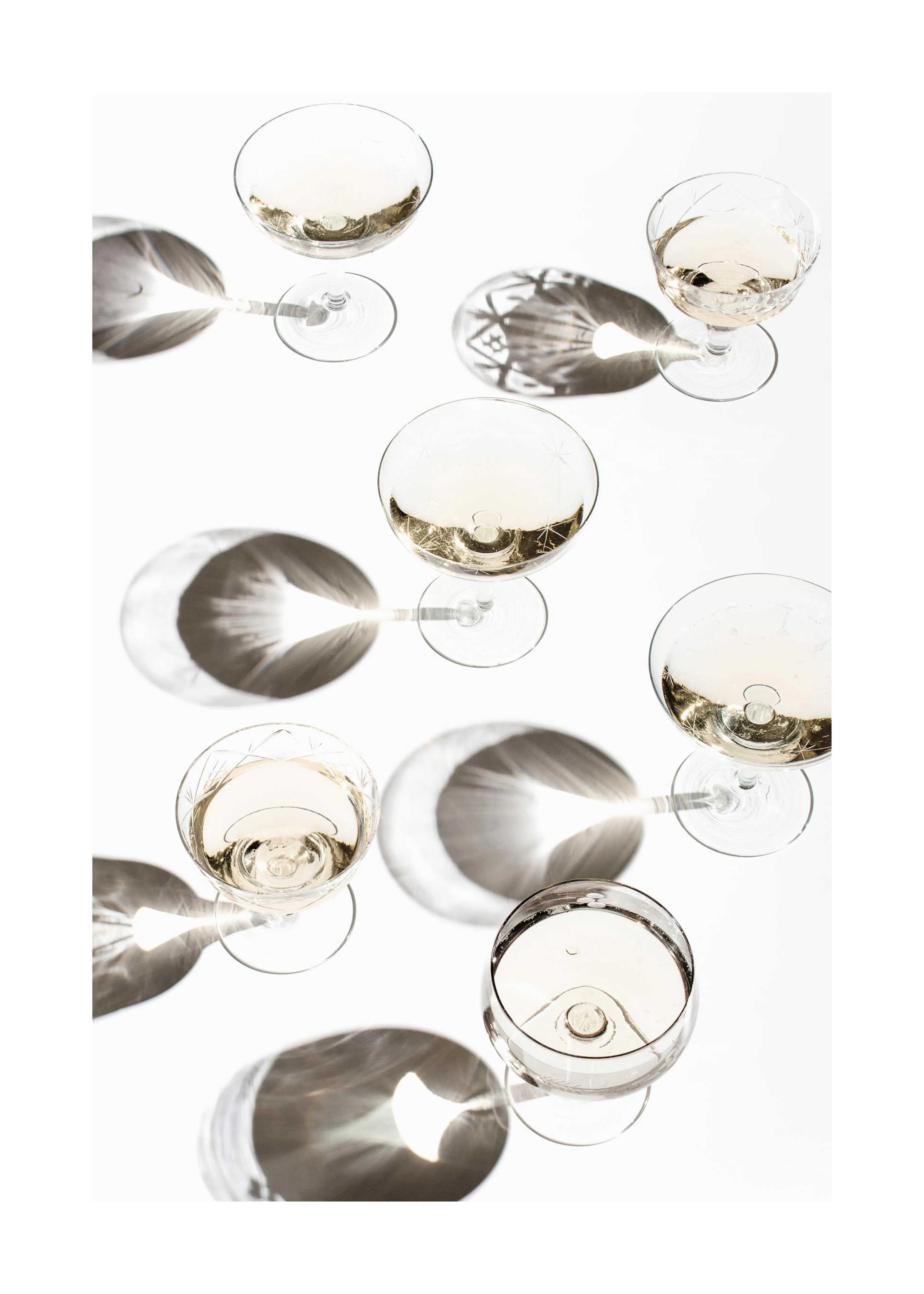 Poster de verres à cocktail remplis dune boisson gazeuse claire avec des ombres grises sur un fond blanc.