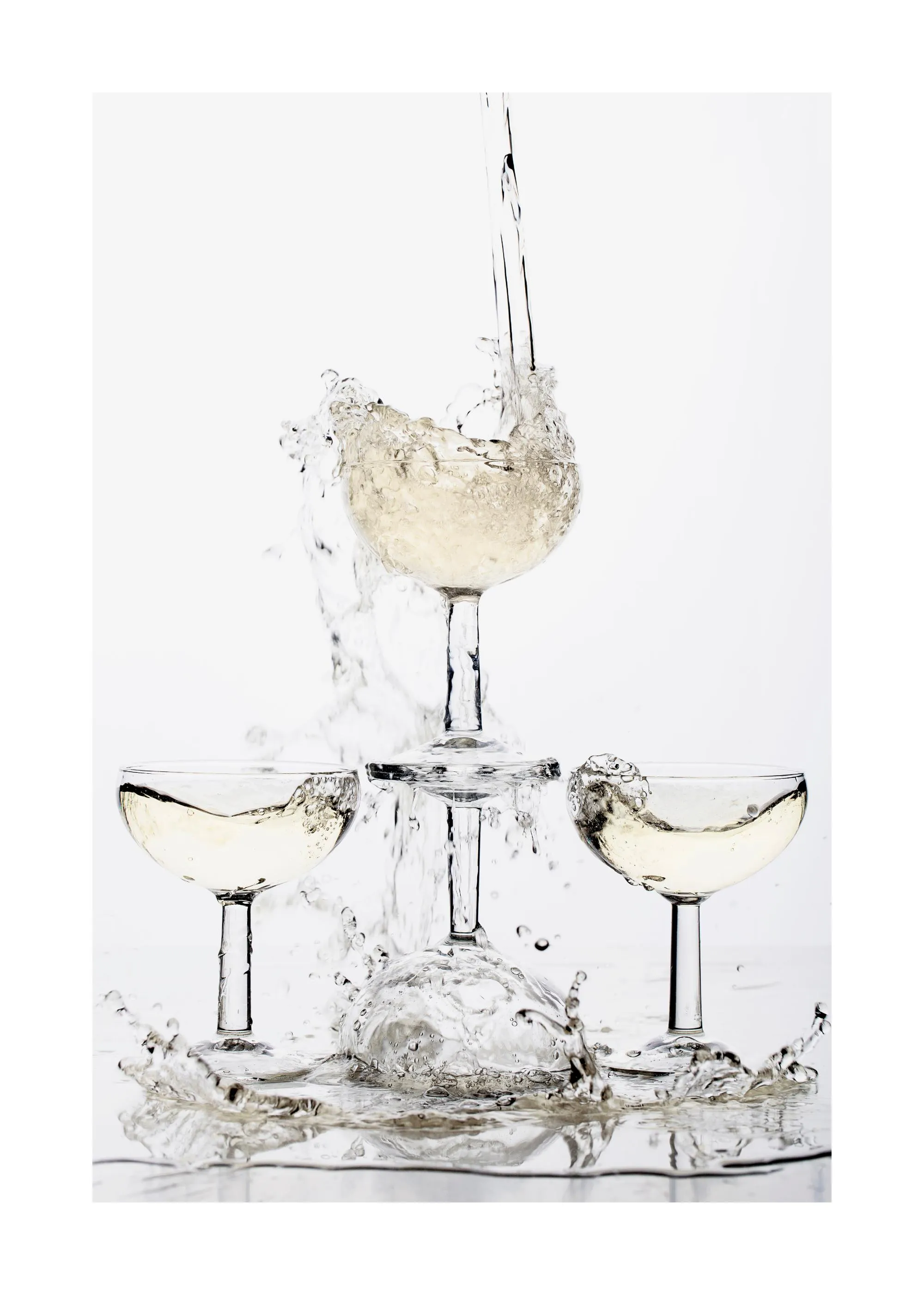 En plakat af champagne der hældes i glas, som danner en pyramide, med stænk af væske rundt om.