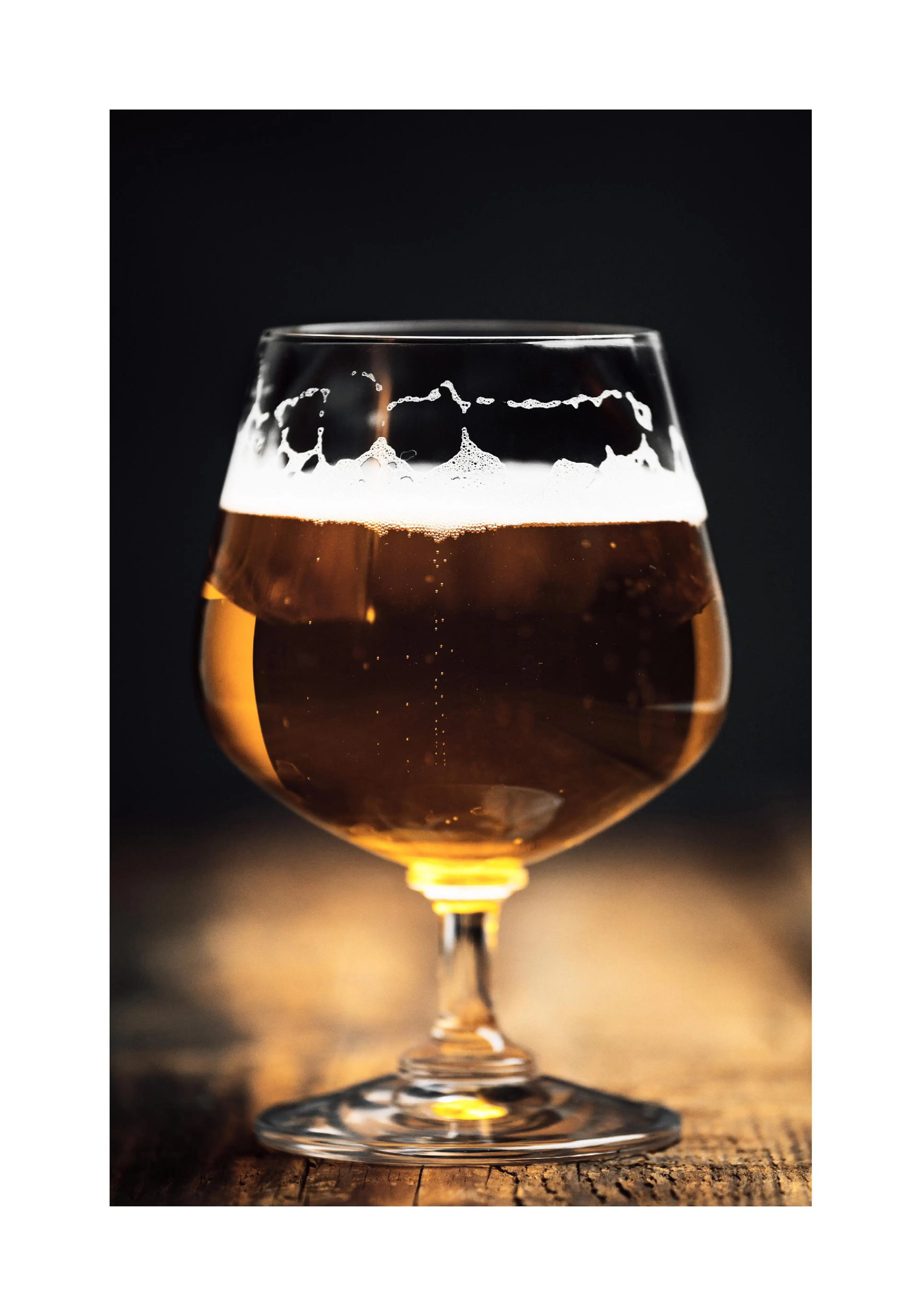 A poster featuring a glass of golden beer with a foamy head and bubbles, on a rustic wooden surface.