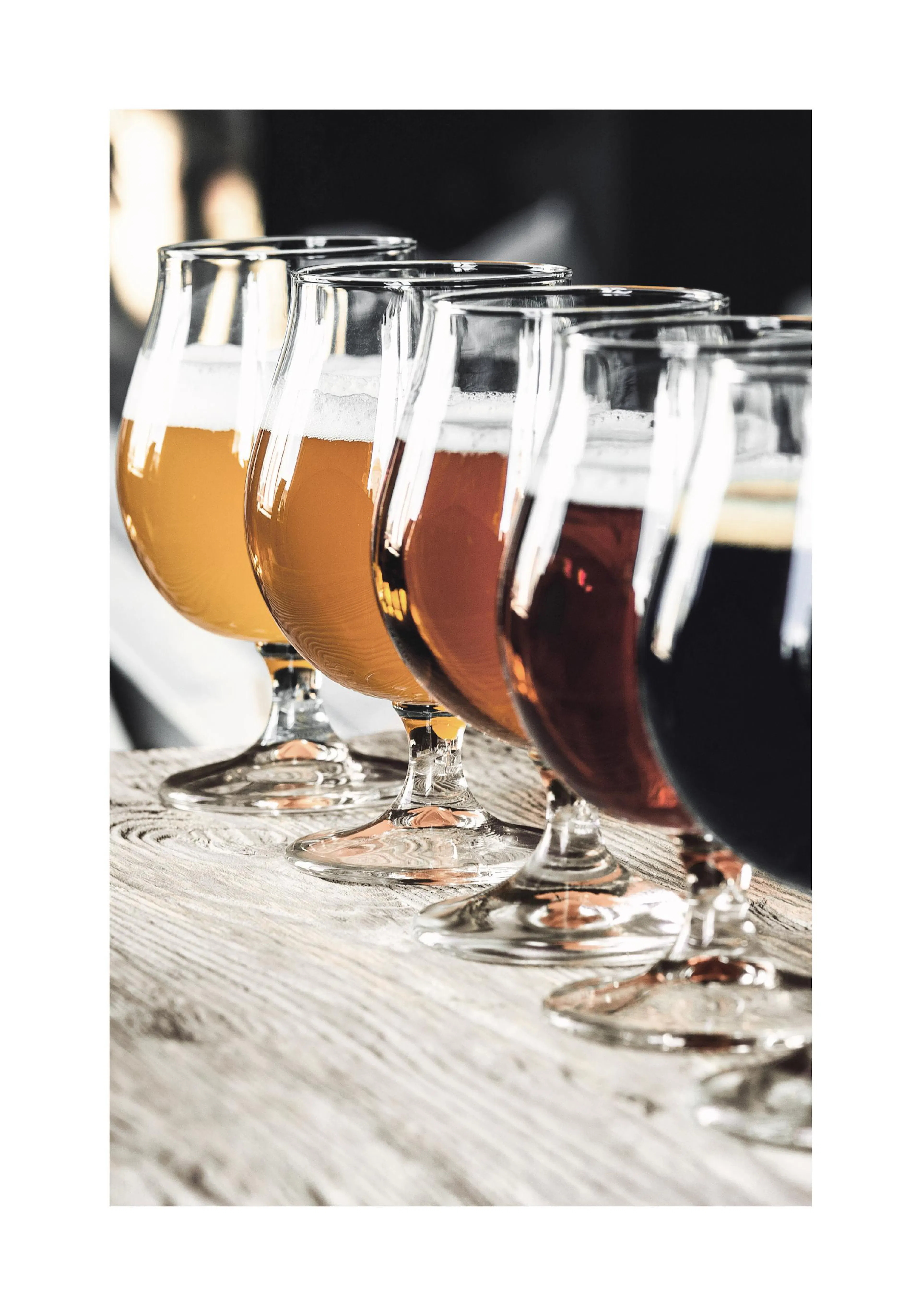 A poster featuring five glasses of beer from light amber to dark brown, lined up on a rustic wooden surface.