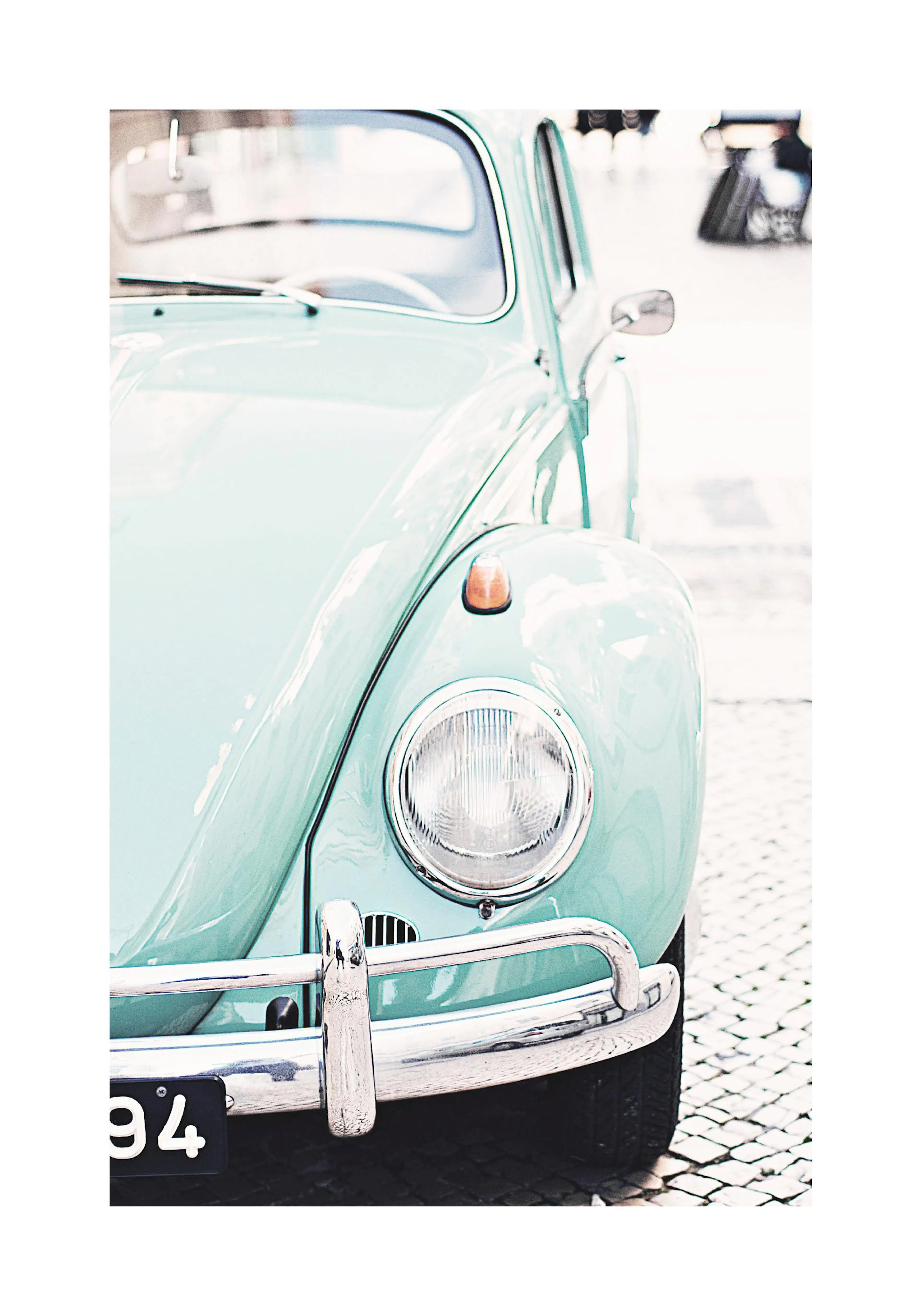 A poster featuring the front right side of a vintage mint green Volkswagen Beetle on cobblestones.