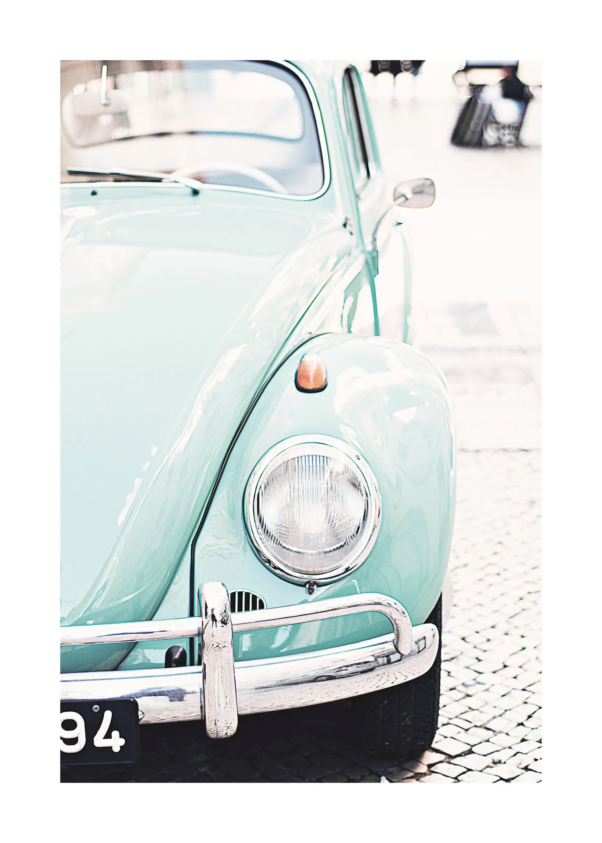 A poster featuring the front right side of a vintage light blue Volkswagen Beetle car with chrome bumper and headlight.