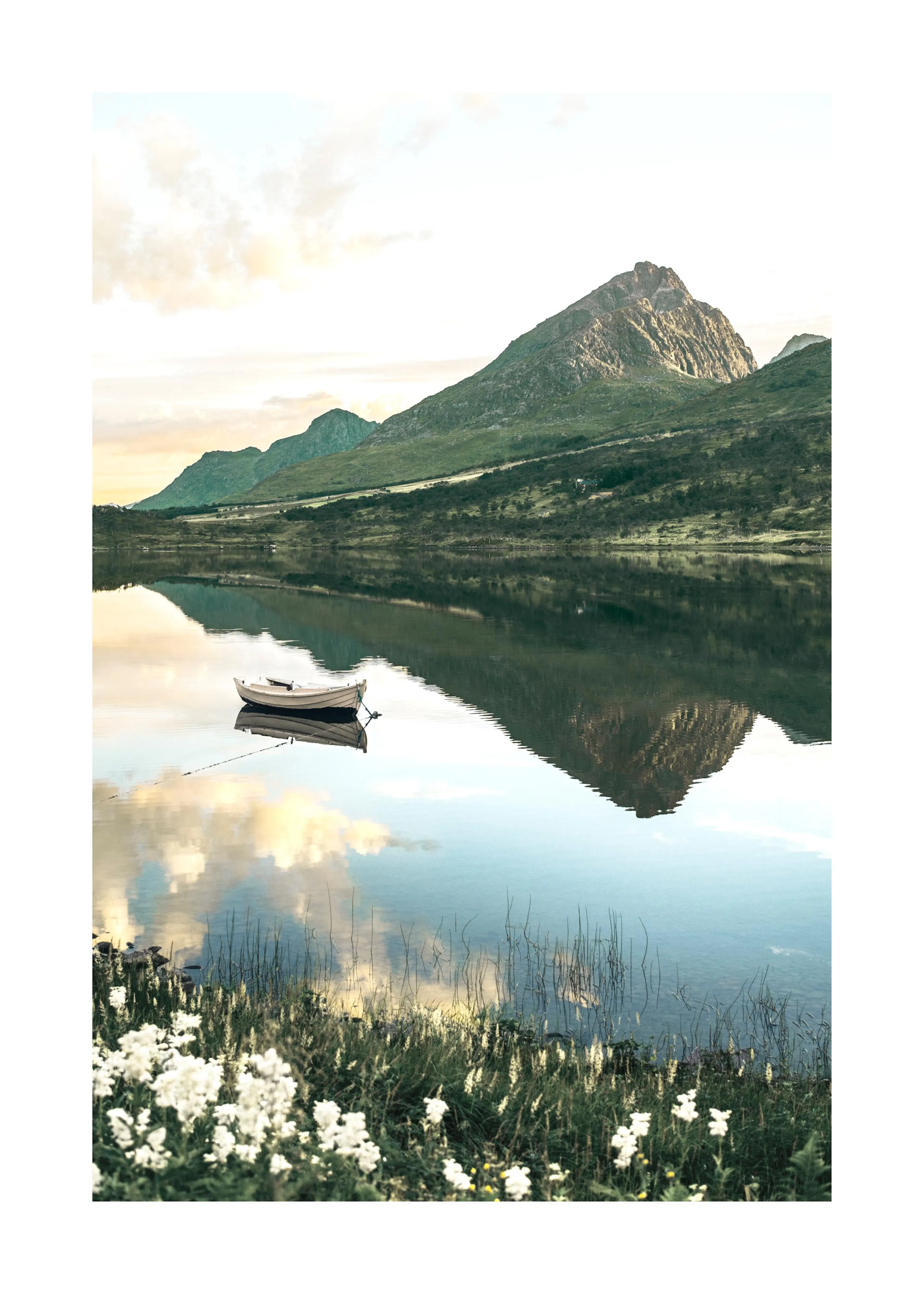 Poster dun bateau sur un lac reflétant des montagnes et le ciel nuageux au lever du soleil, avec des fleurs blanches au premier 