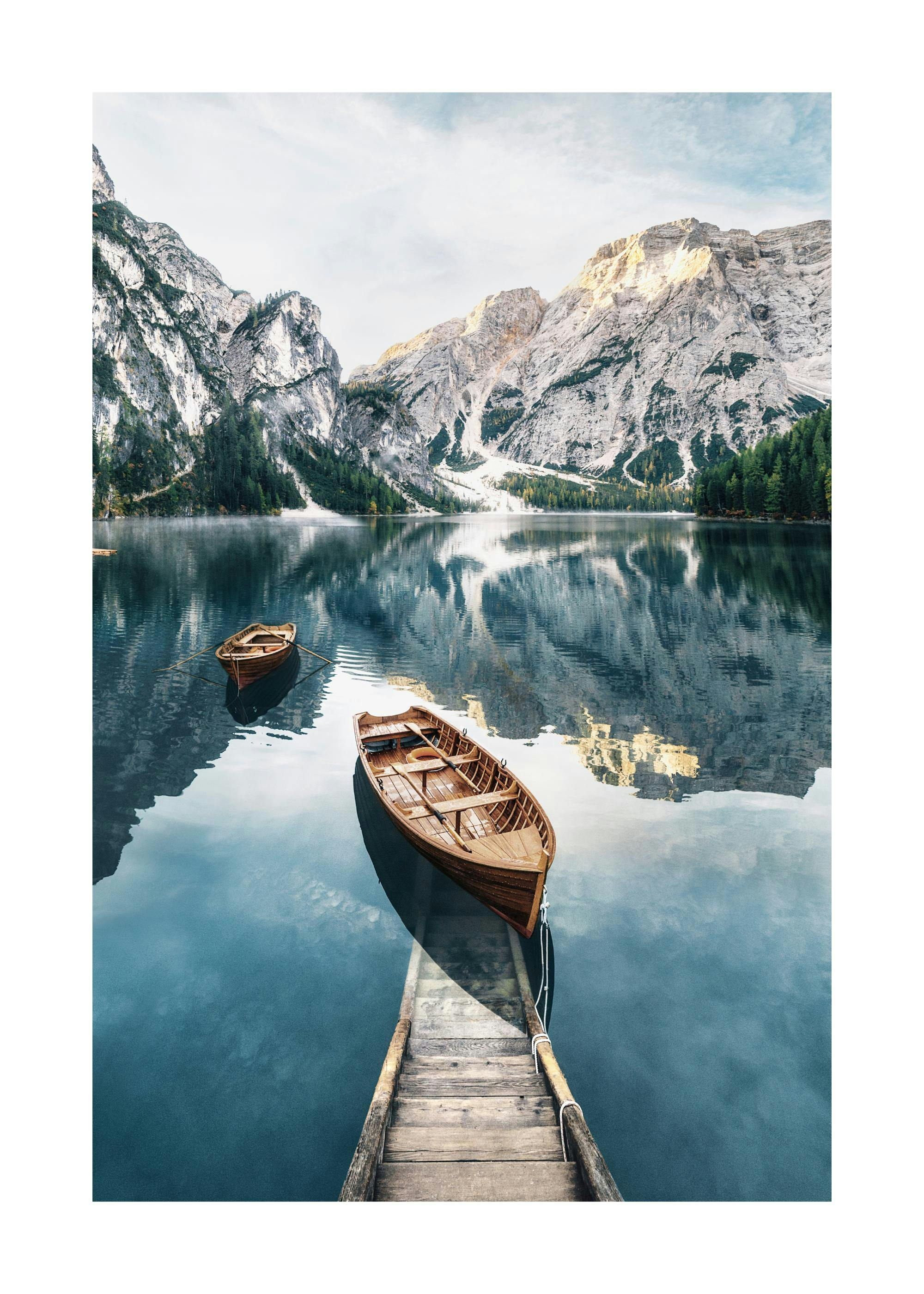 Plakát s jezerem Braies, horami Dolomit a dřevěnými lodičkami s vesly na klidné vodě.