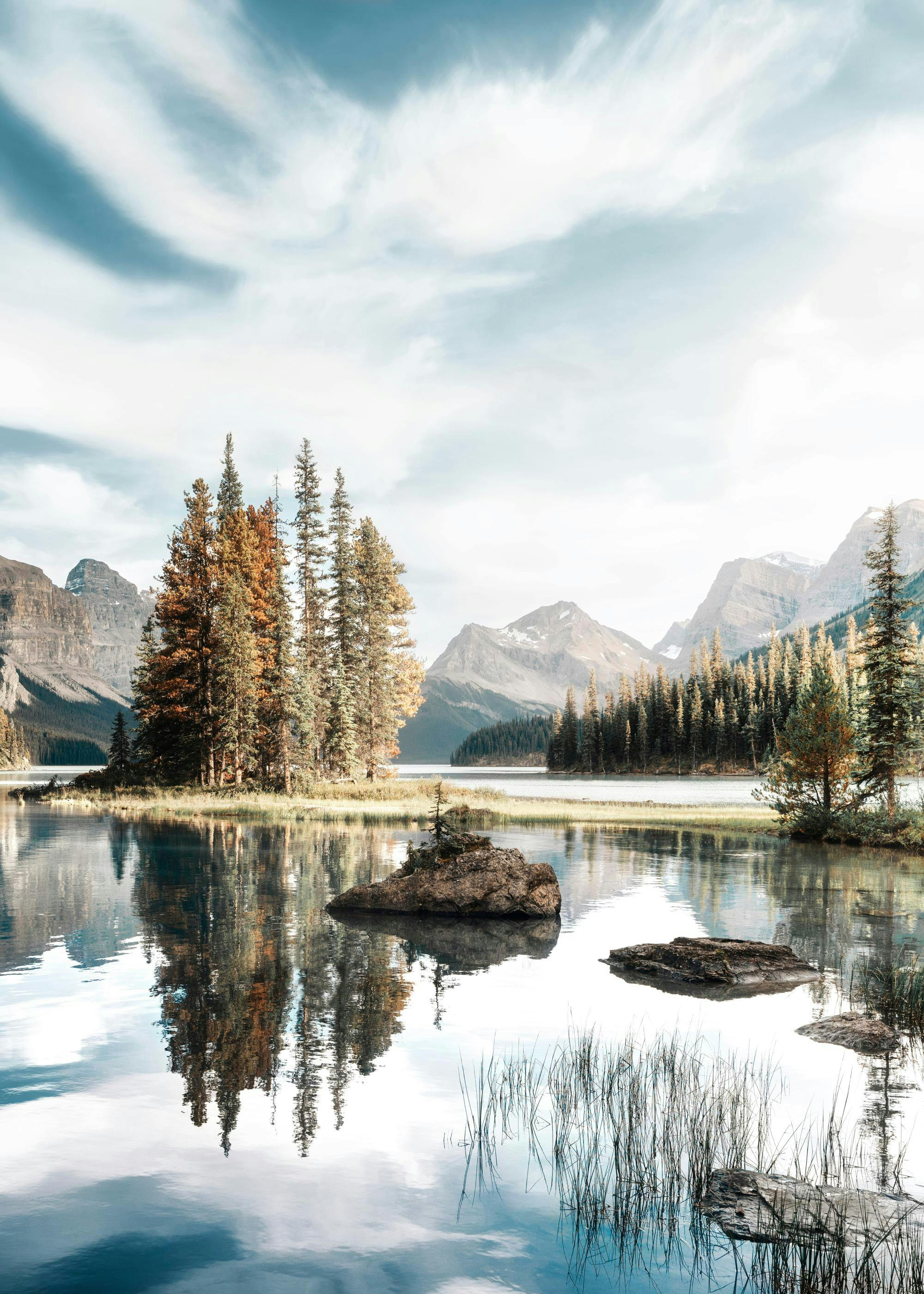 A poster featuring a tranquil lake scene with green and autumn trees on an island, reflected in the calm water, under a bright s