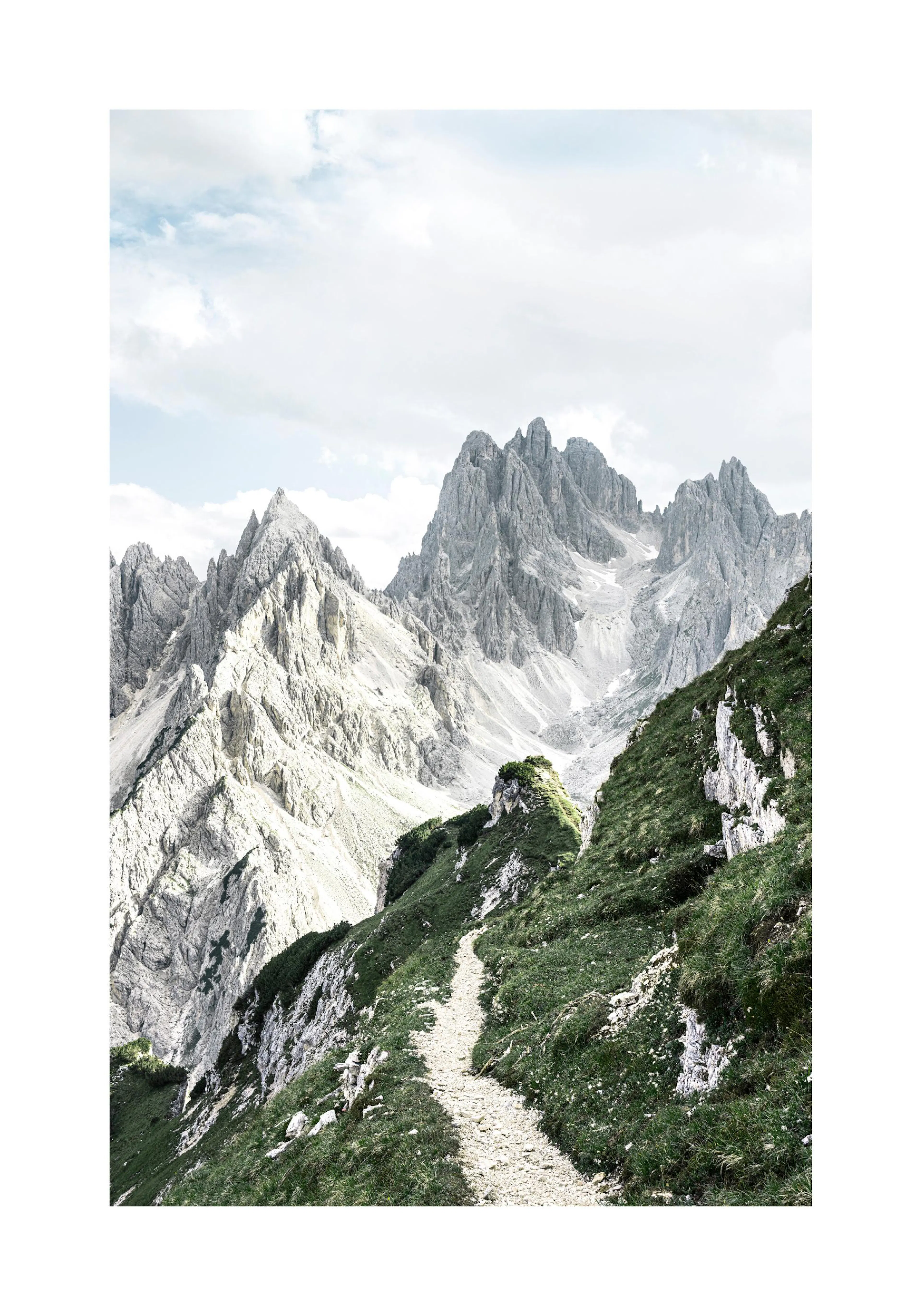 A poster featuring a winding path on a green, rocky hillside leading towards jagged grey mountains under a cloudy sky.