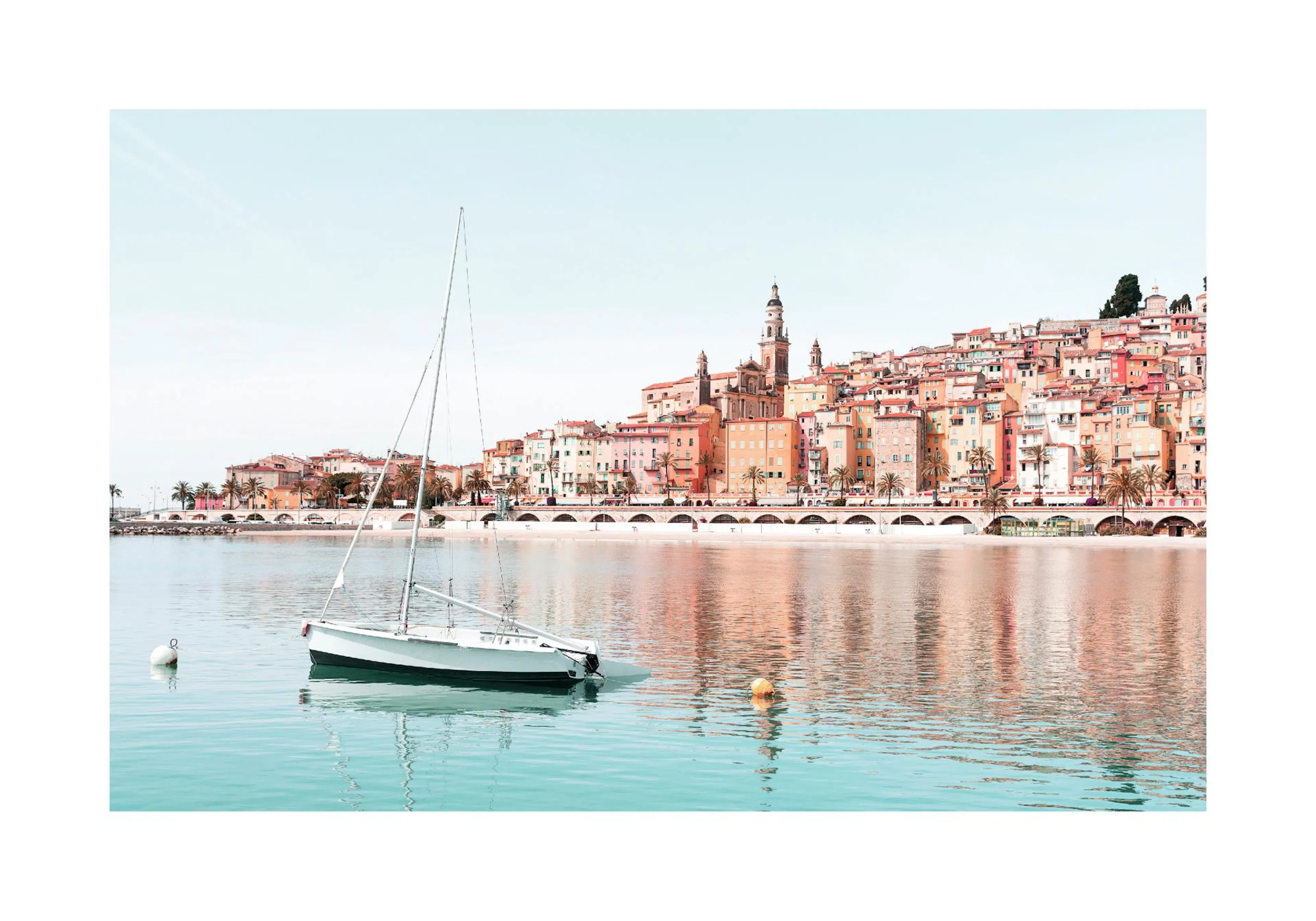 A poster featuring a white sailboat on turquoise water with a colourful coastal town and palm trees reflecting in the distance.