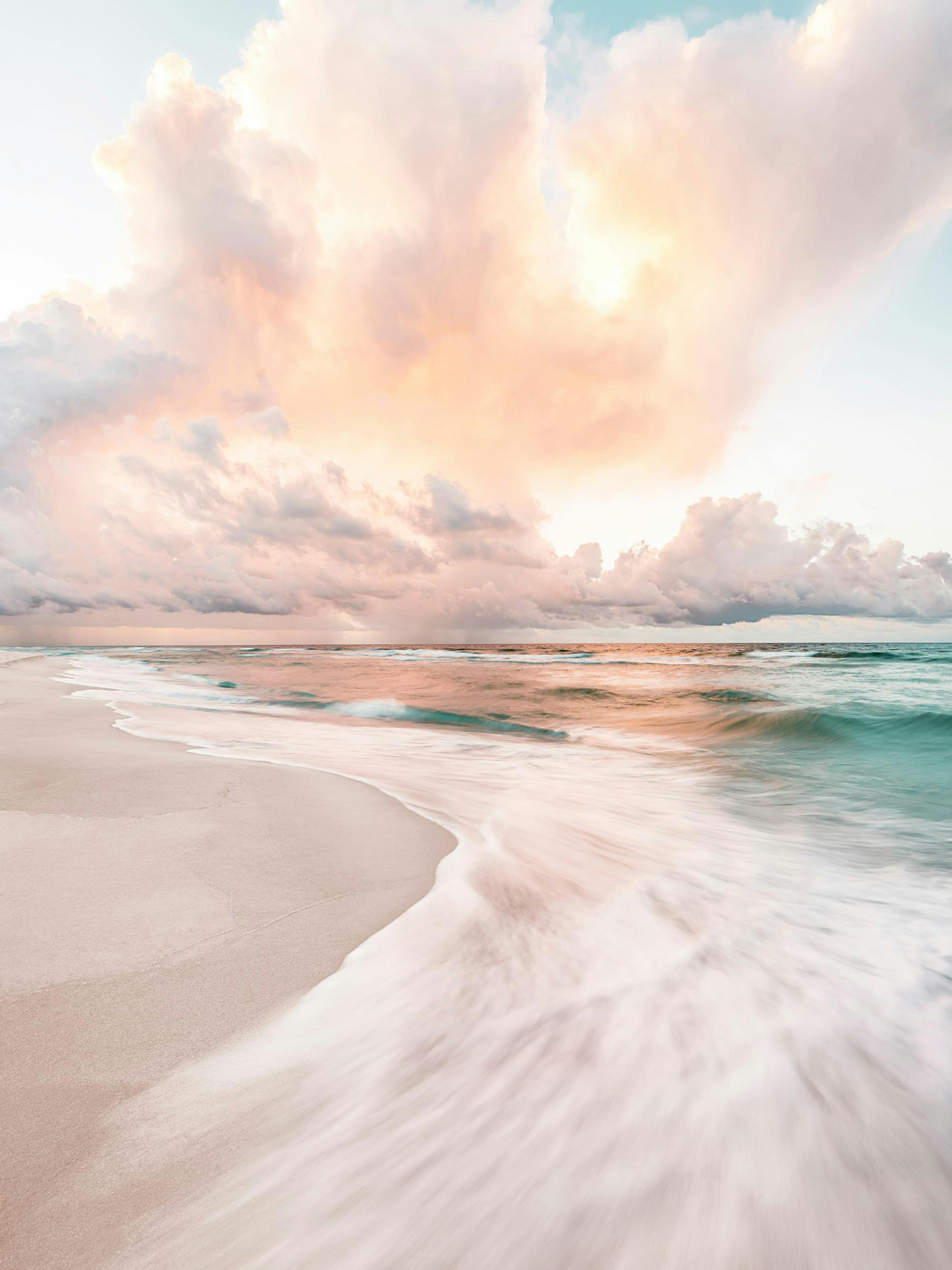 A poster depicting a serene beach scene with calm turquoise ocean waves washing onto the light sand under a pastel pink and oran