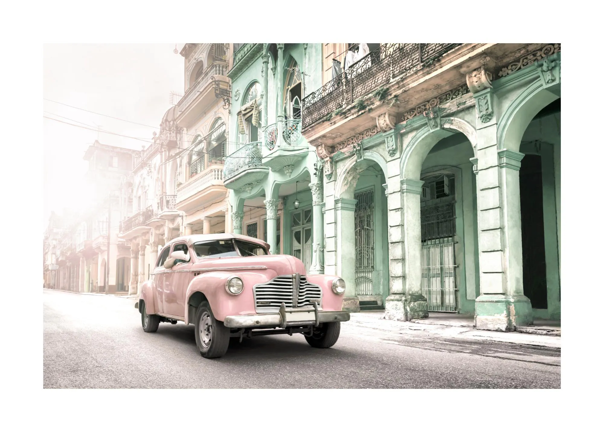Plakát s růžovým historickým autem na ulici v Havaně, lemované starými barevnými budovami.