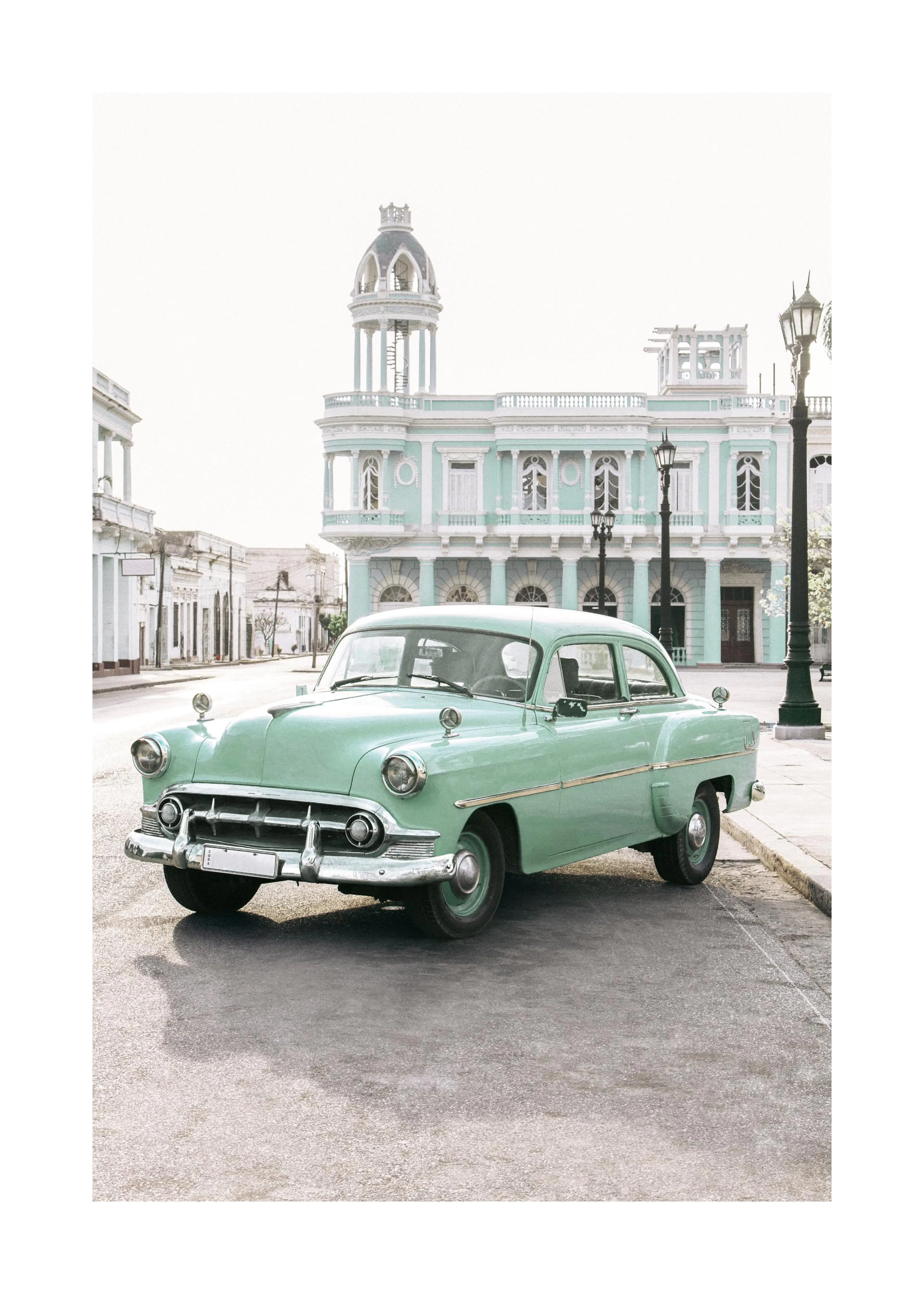 Plakát s tyrkysovým historickým autem na ulici před pastelově zelenou budovou s kupolí, na Kubě.