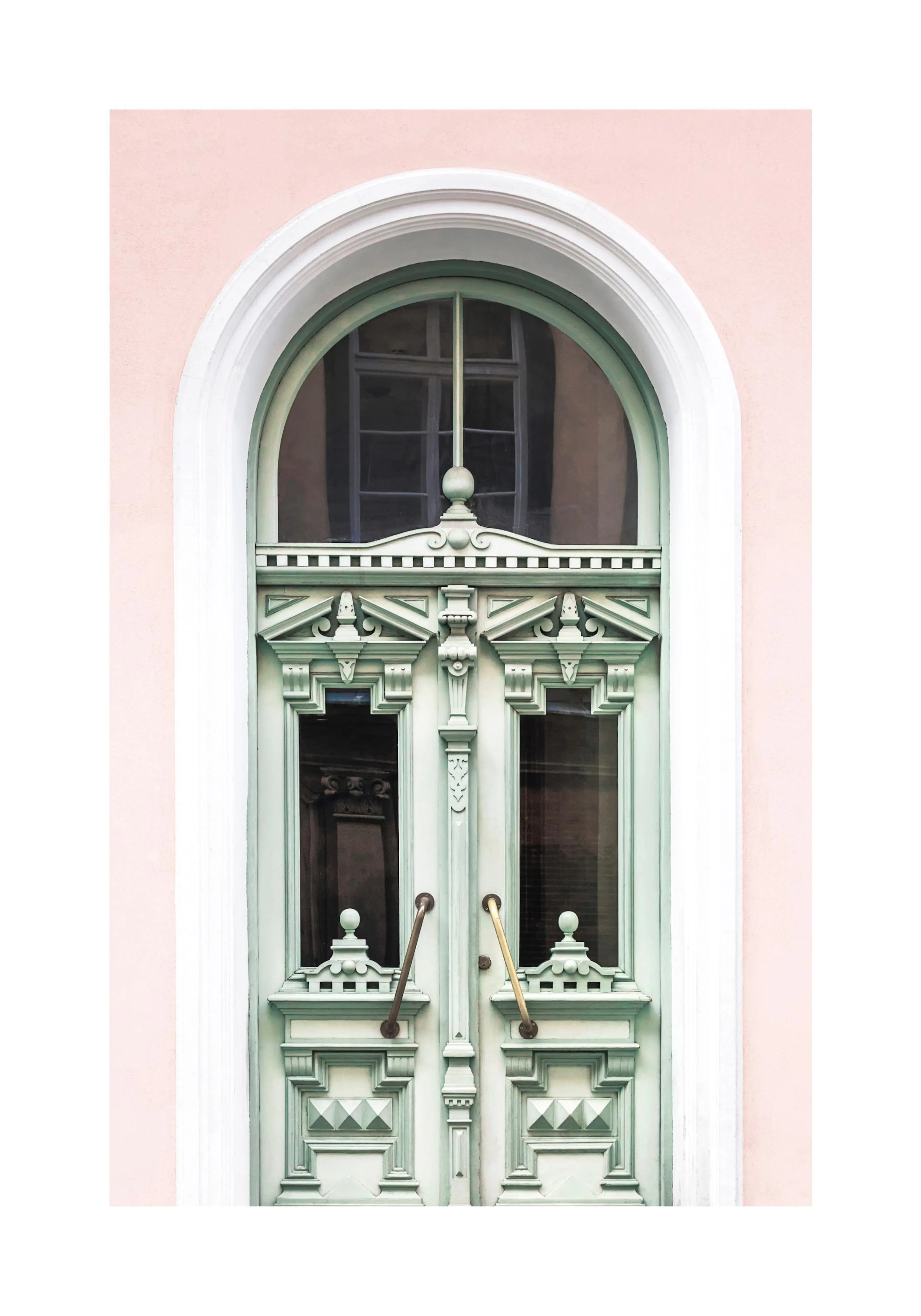 Un poster di unantica porta verde menta con intagli dettagliati e maniglie in ottone, incorniciata da un muro rosa chiaro.