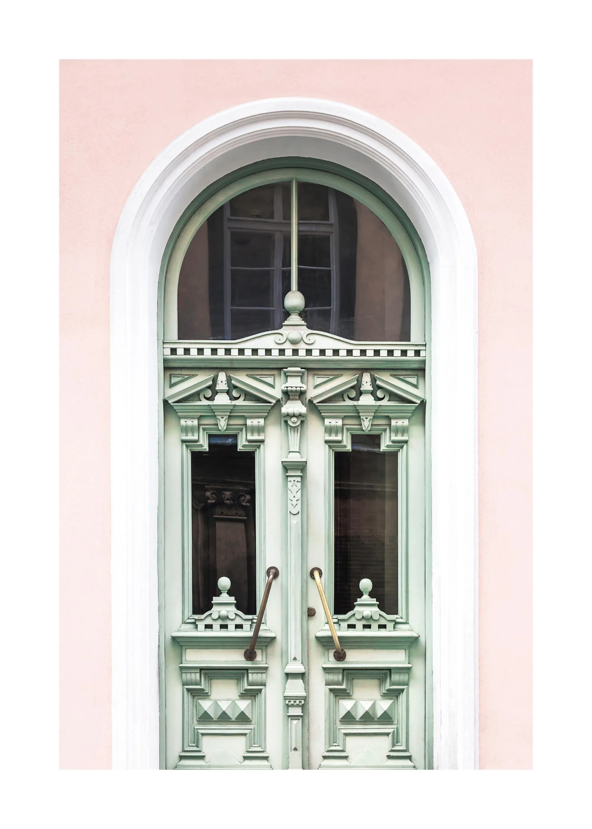 Un poster di unantica porta verde menta con intagli dettagliati e maniglie in ottone, incorniciata da un muro rosa chiaro.