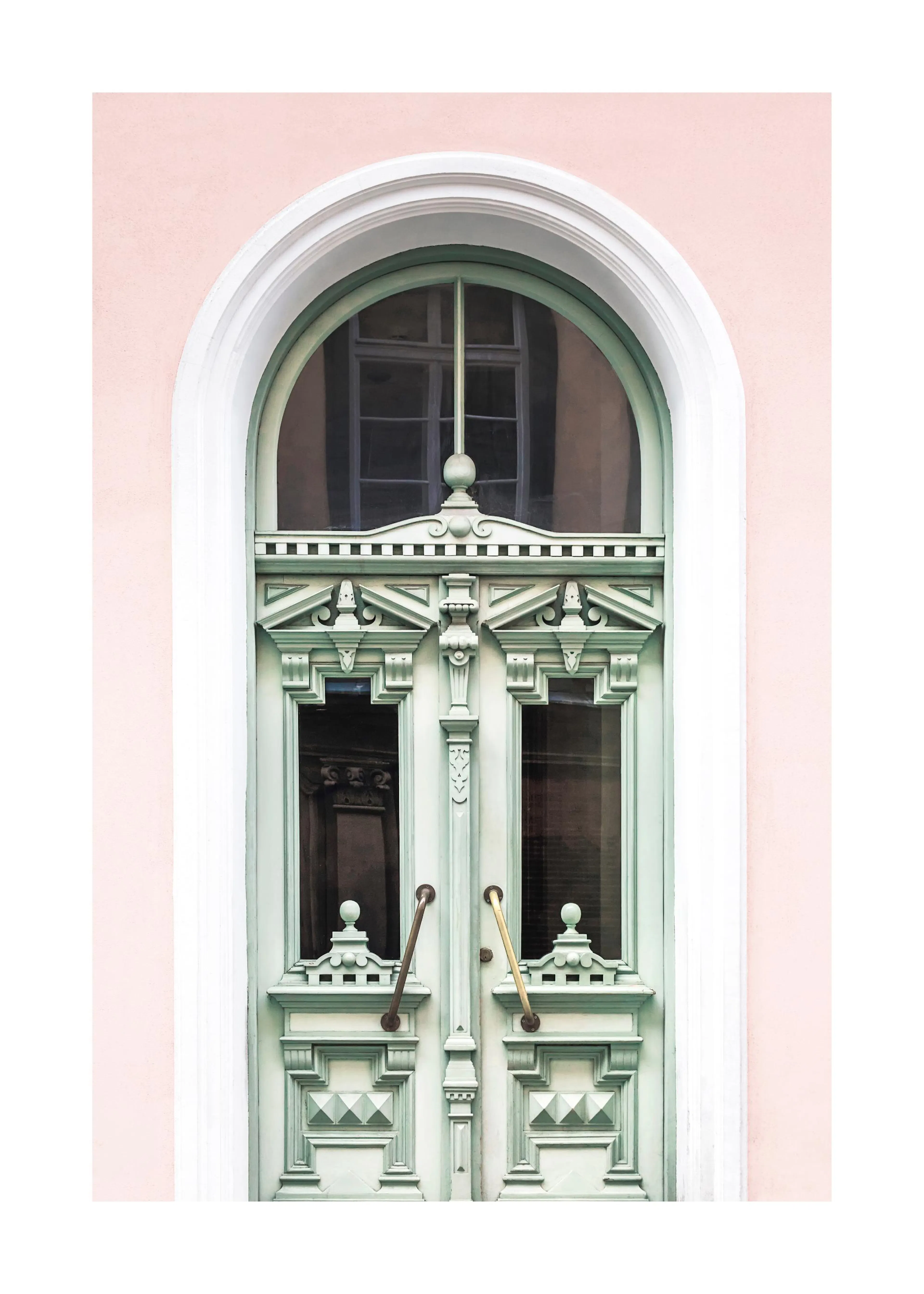 Un poster di unantica porta verde menta con intagli dettagliati e maniglie in ottone, incorniciata da un muro rosa chiaro.