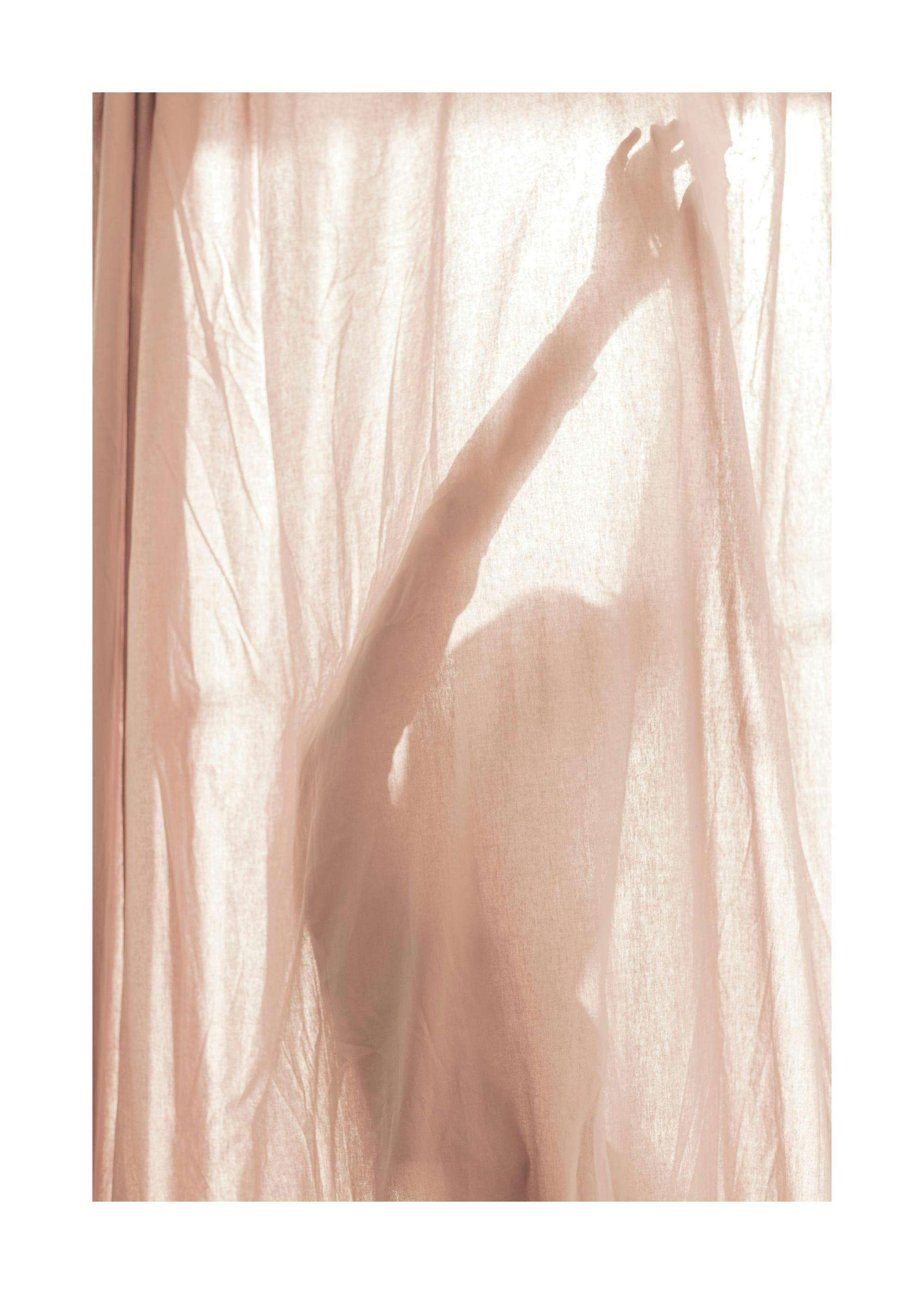 Póster de una silueta de persona con un brazo levantado, visible a través de una tela rosa pálido iluminada por el sol.