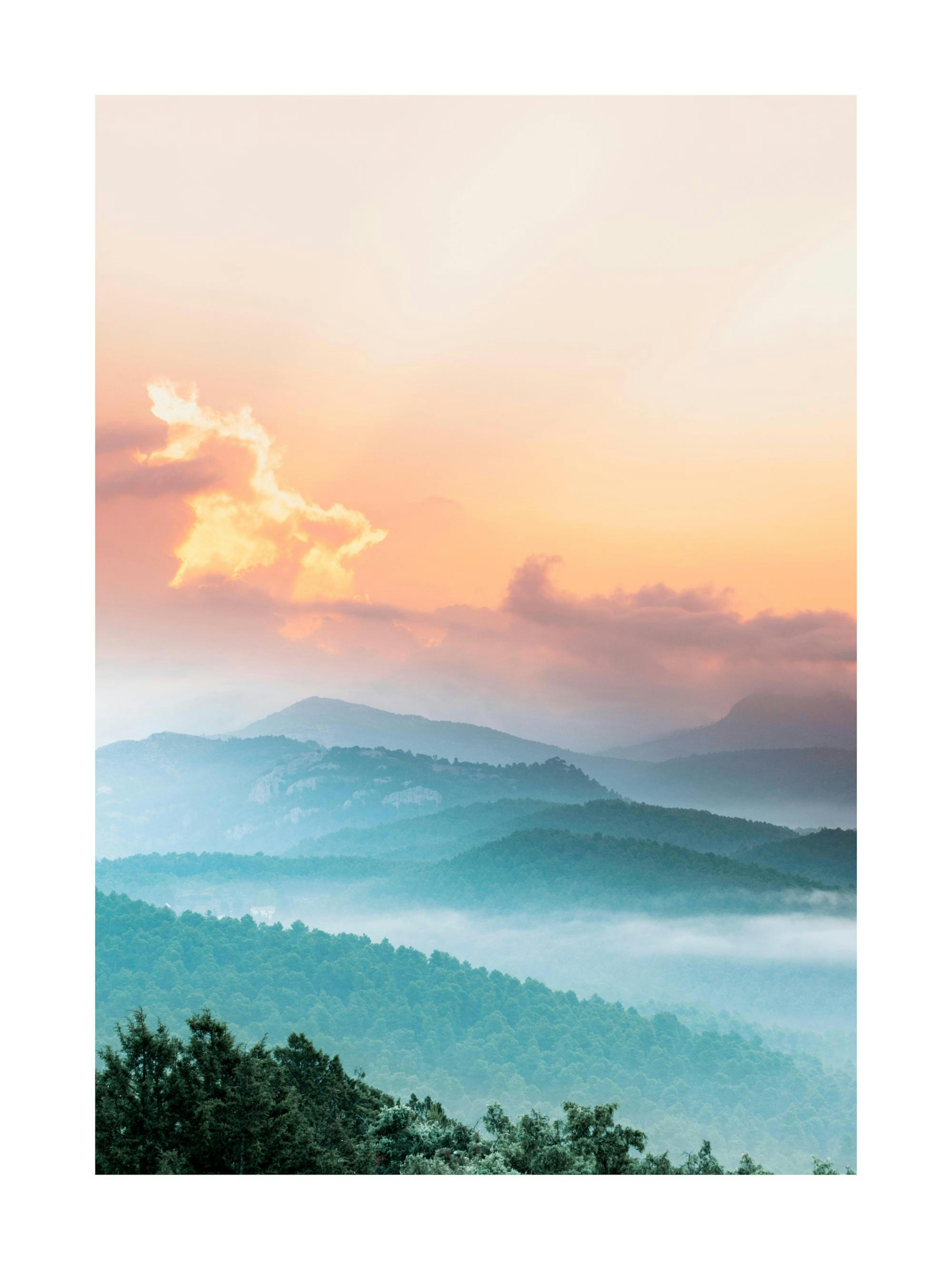 A poster featuring misty blue mountains and green forest under a vibrant orange and pink sunset sky.