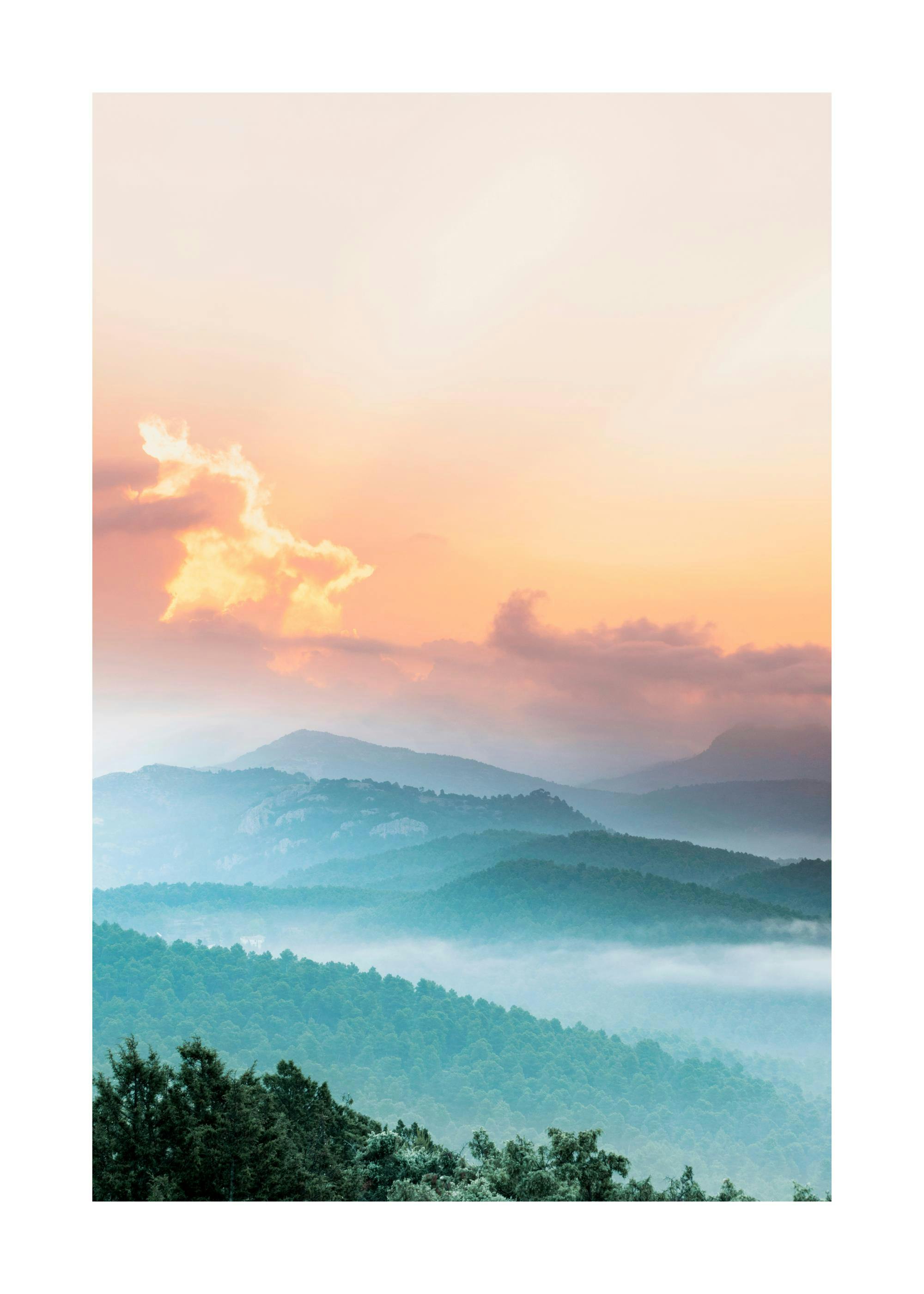 Poster einer Landschaft mit grünen Bergen und Nebel bei Sonnenuntergang, der den Himmel orange und rosa färbt.