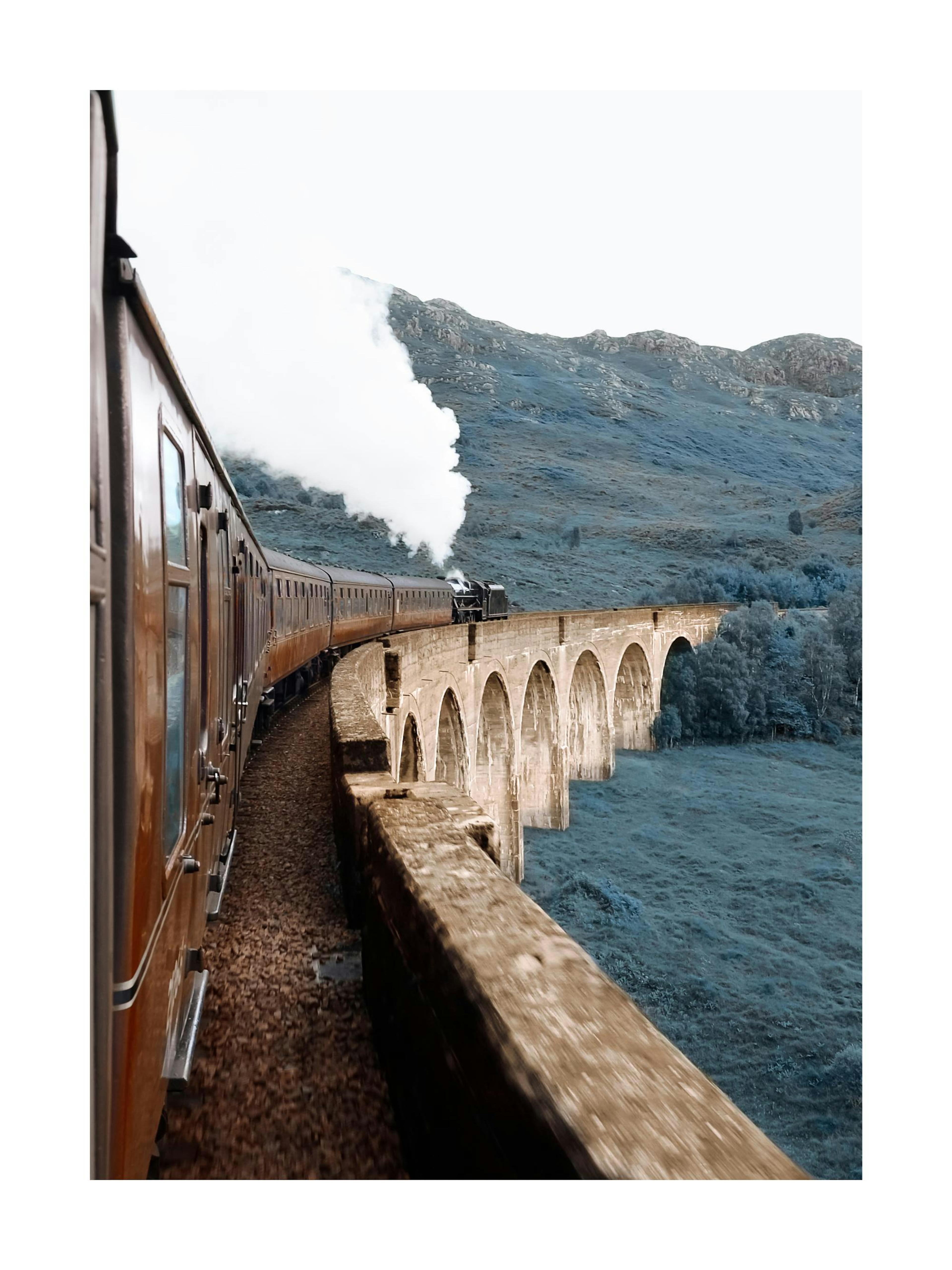 Póster de un tren de vapor cruzando un viaducto de arcos, con montañas y vegetación de fondo.