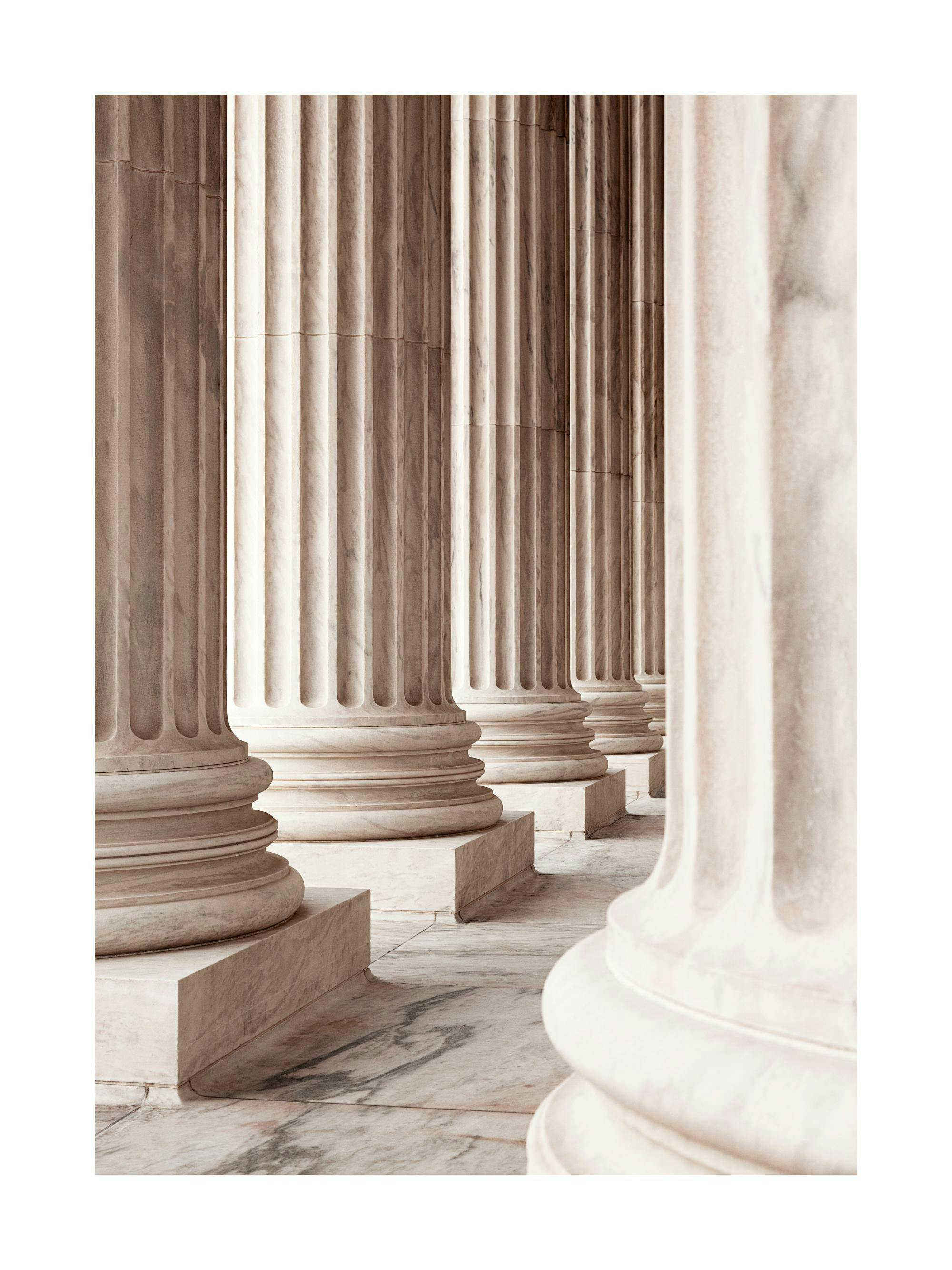 Poster de colonnes en marbre beige clair avec des bases sculptées, créant une perspective architecturale.