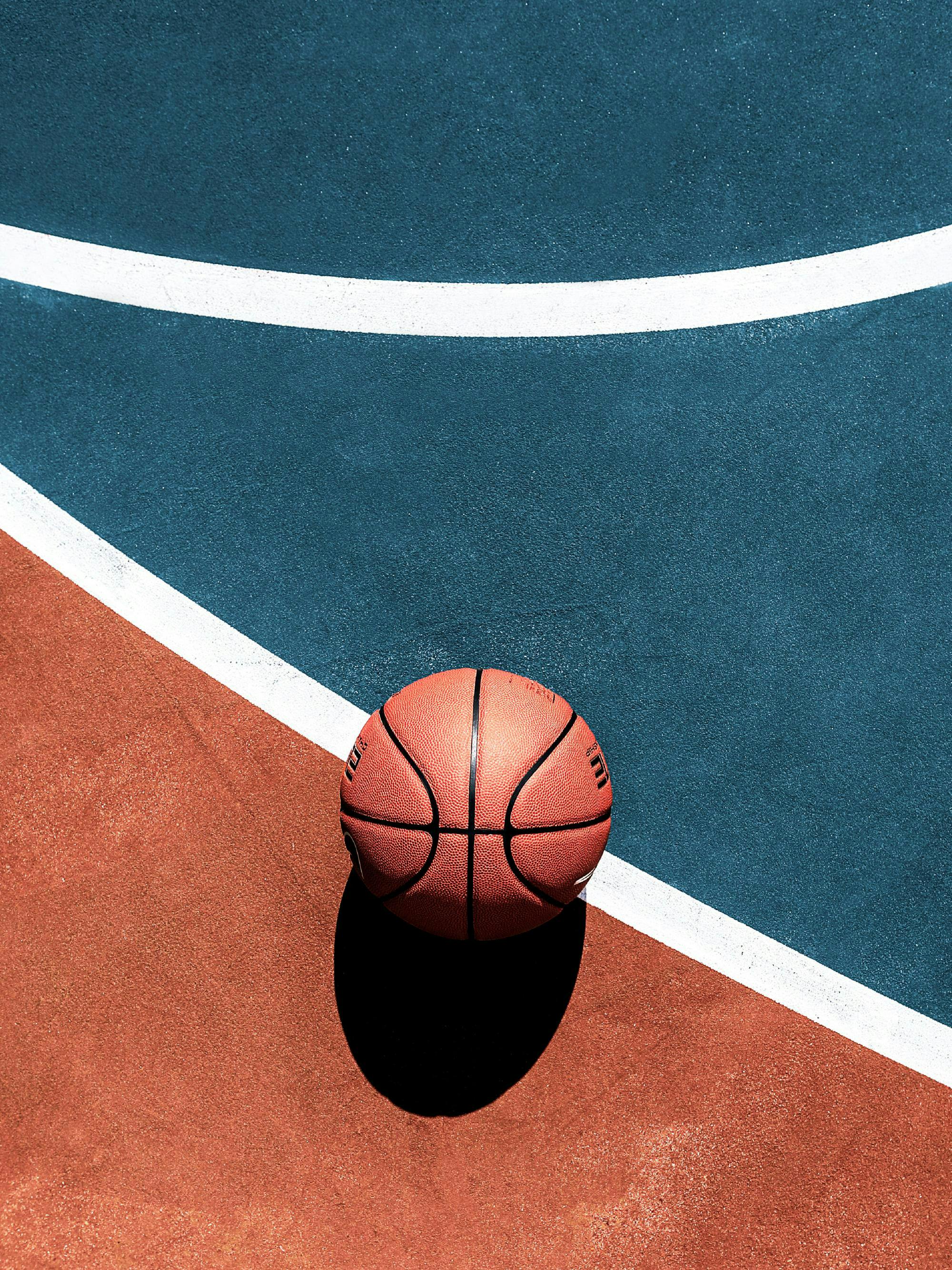 En poster av en basketboll på en orange och blå basketplan med vita linjer.