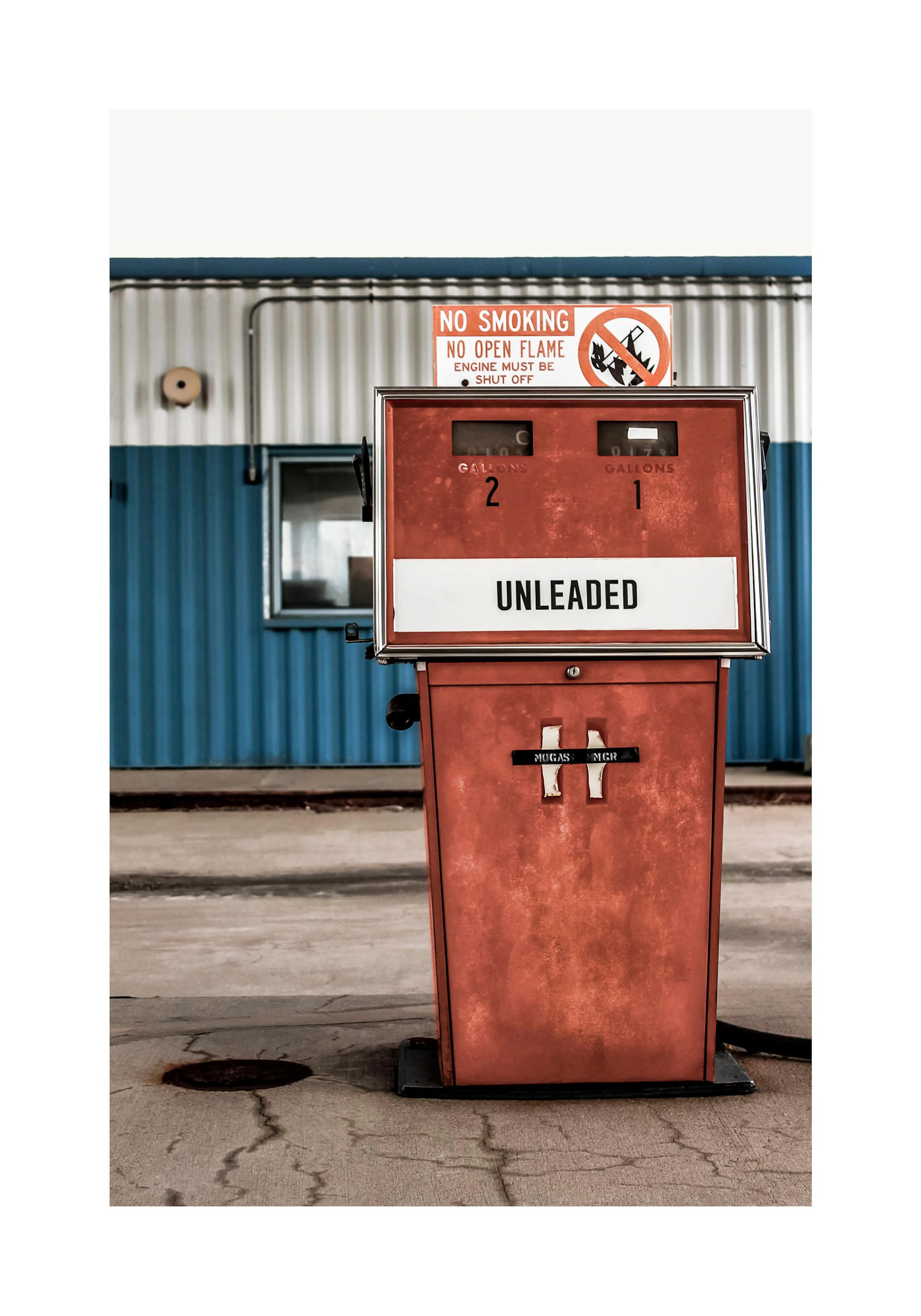 En poster med en vintage röd bensinpump med texten UNLEADED mot en blå och vit vägg.