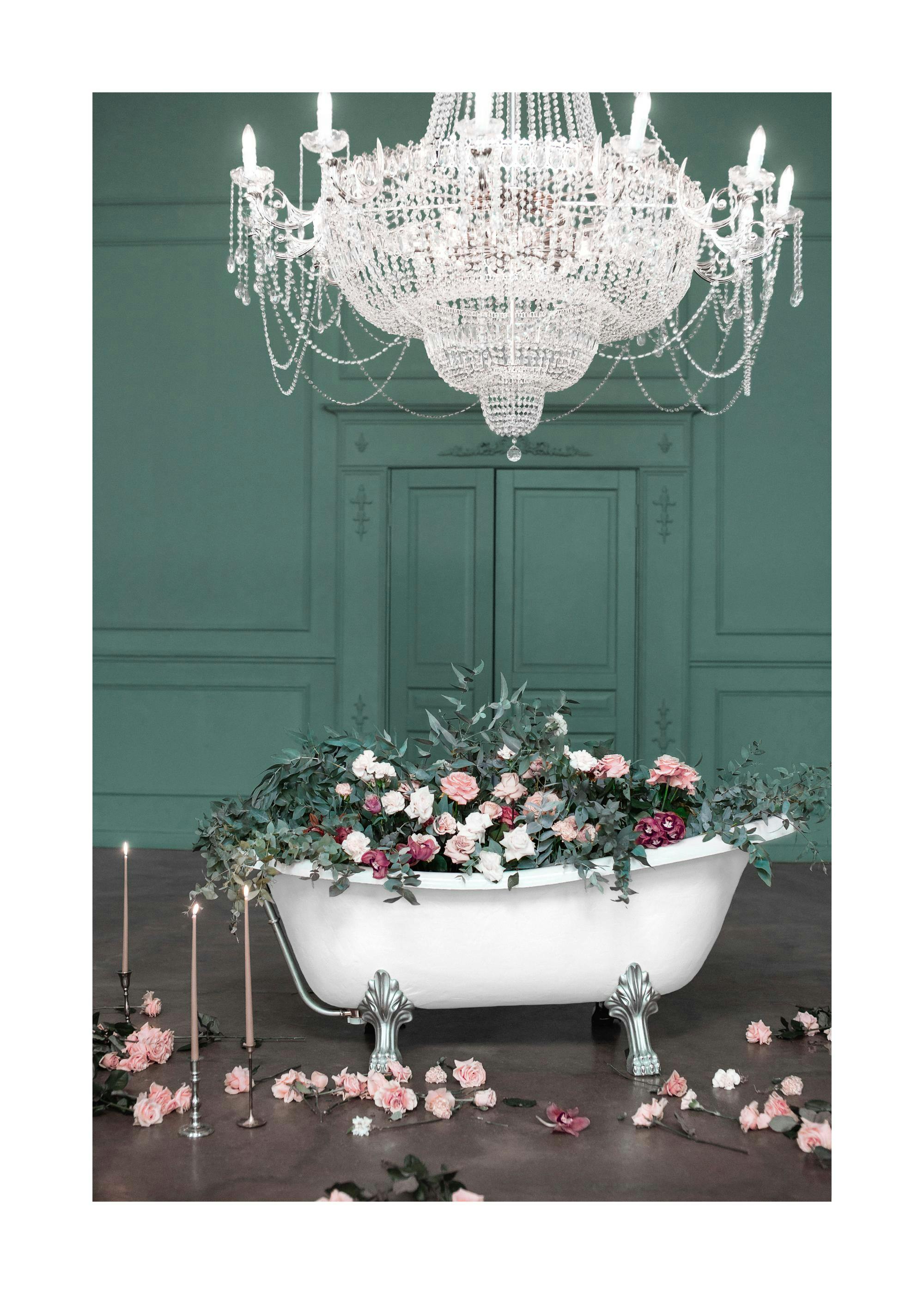 Poster dune baignoire blanche remplie de roses et de verdure, sous un lustre en cristal, avec des bougies allumées et des pétale