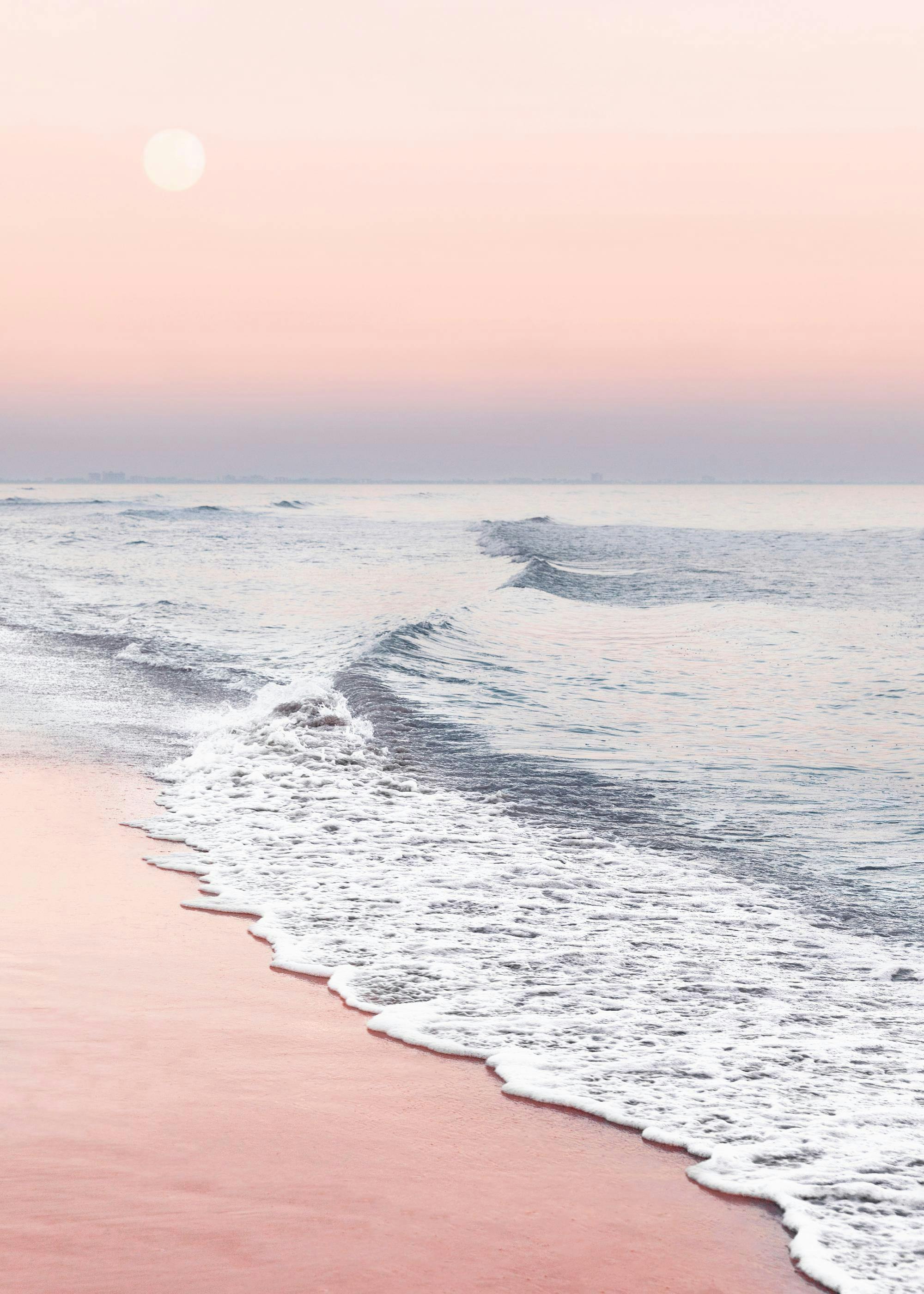 A poster featuring a calming seaside scene with soft pink sand and gentle waves under a pale pink sky with a visible sun.
