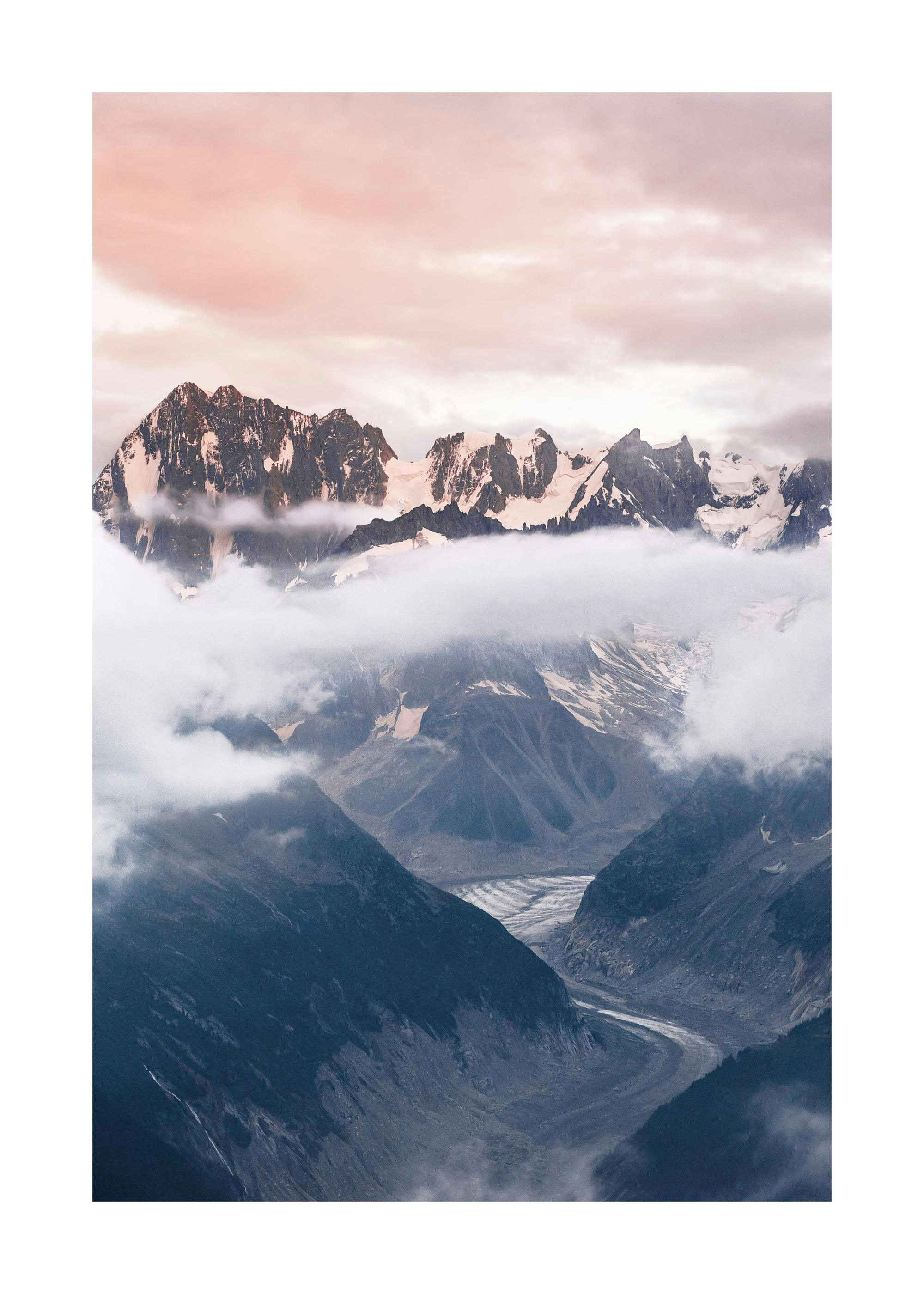 Póster de montañas cubiertas de nieve con nubes que se ciernen sobre los picos y un valle con un glaciar.