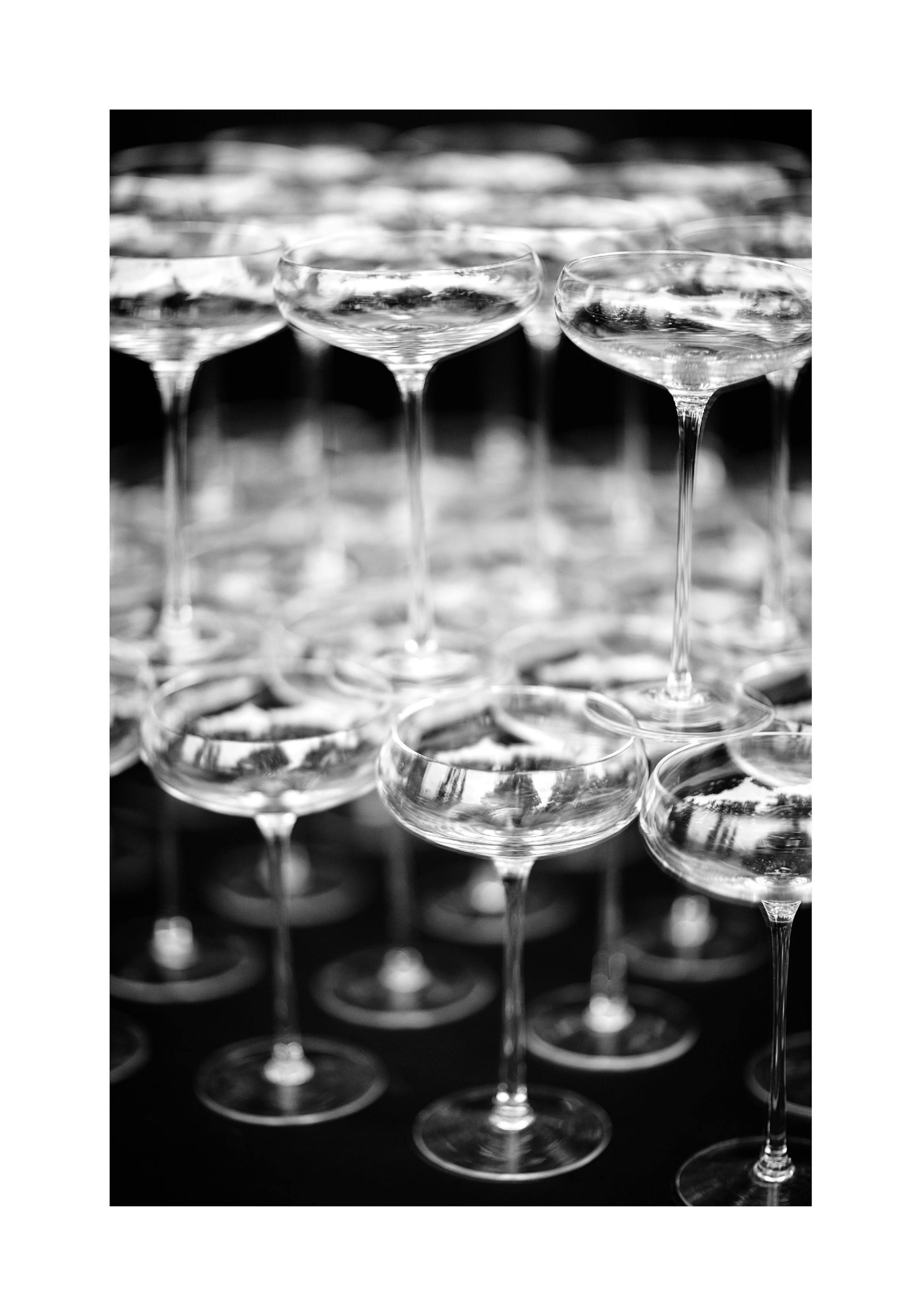 Ein Poster mit einer Pyramide aus Champagnergläsern in Schwarz-Weiss, reflektierend und schimmernd.