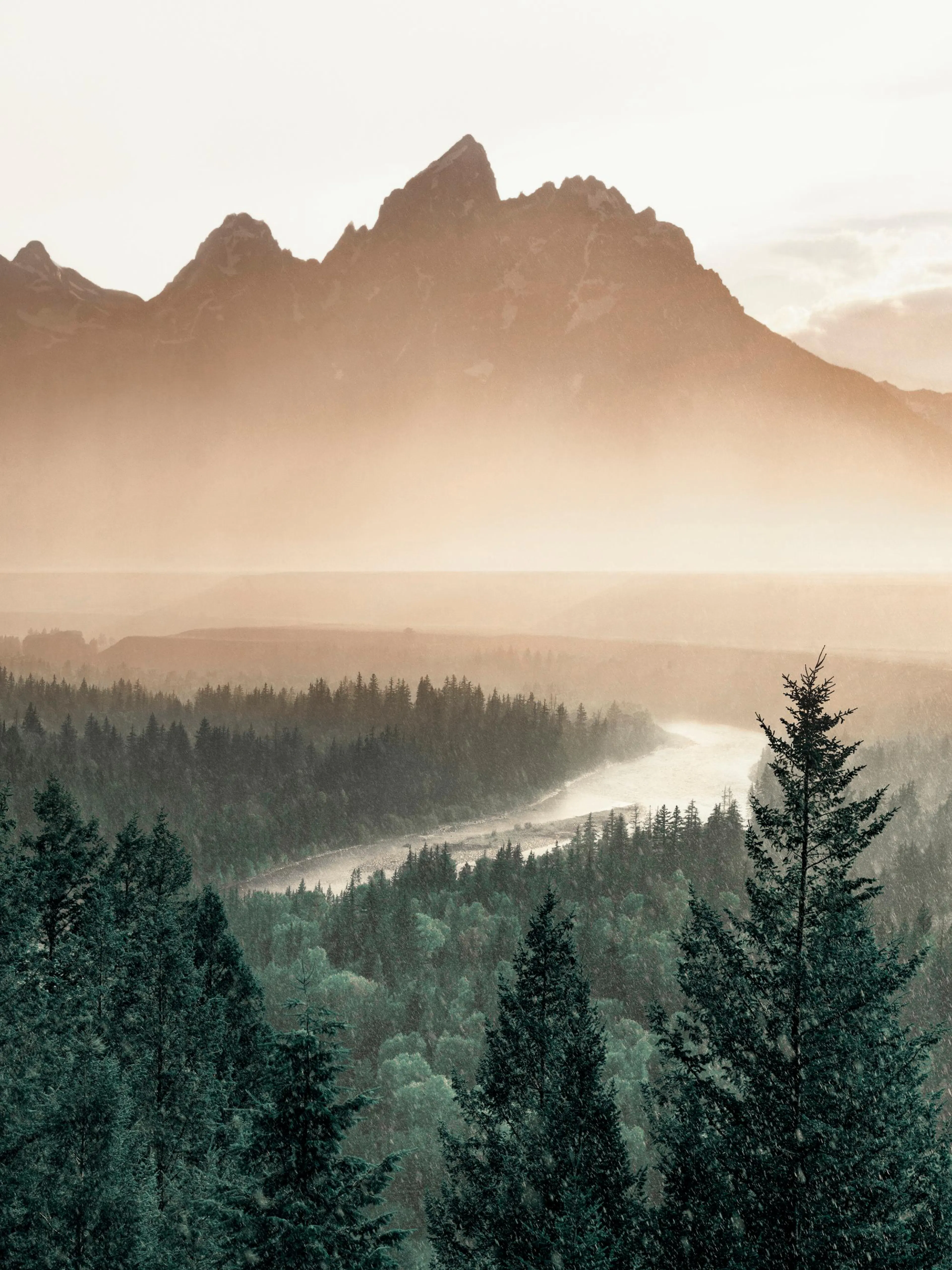 Póster de montañas brumosas al atardecer sobre un río serpenteante y un denso bosque verde.